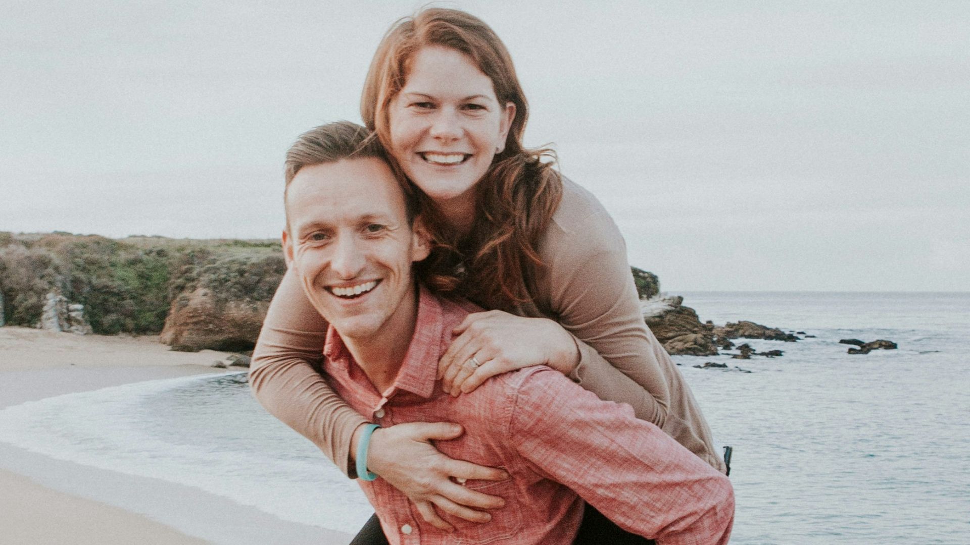 man carrying woman beside seashore