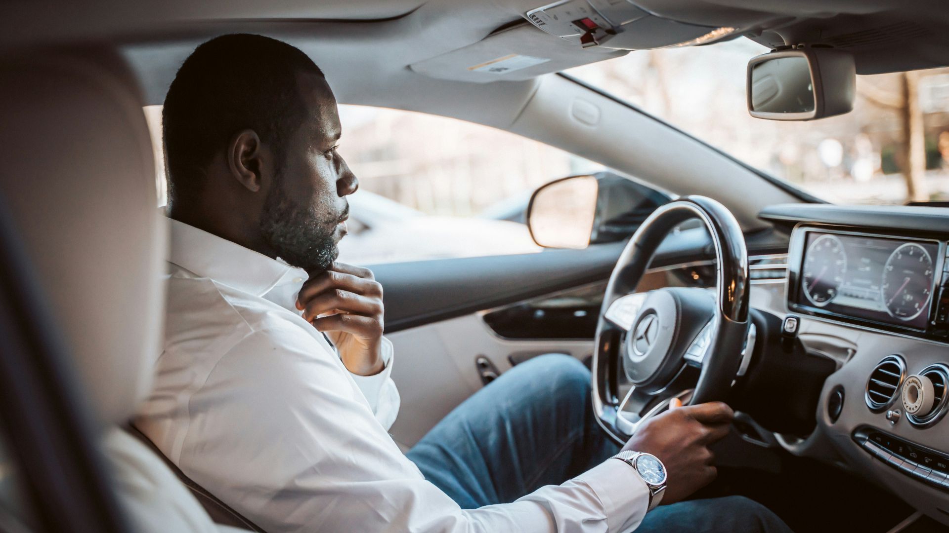 man in white dress shirt driving car during daytime