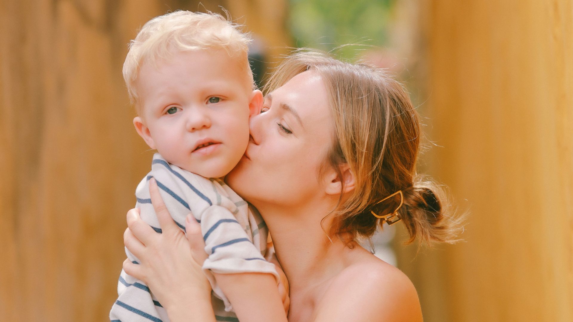 Woman kissing her child in a narrow alley