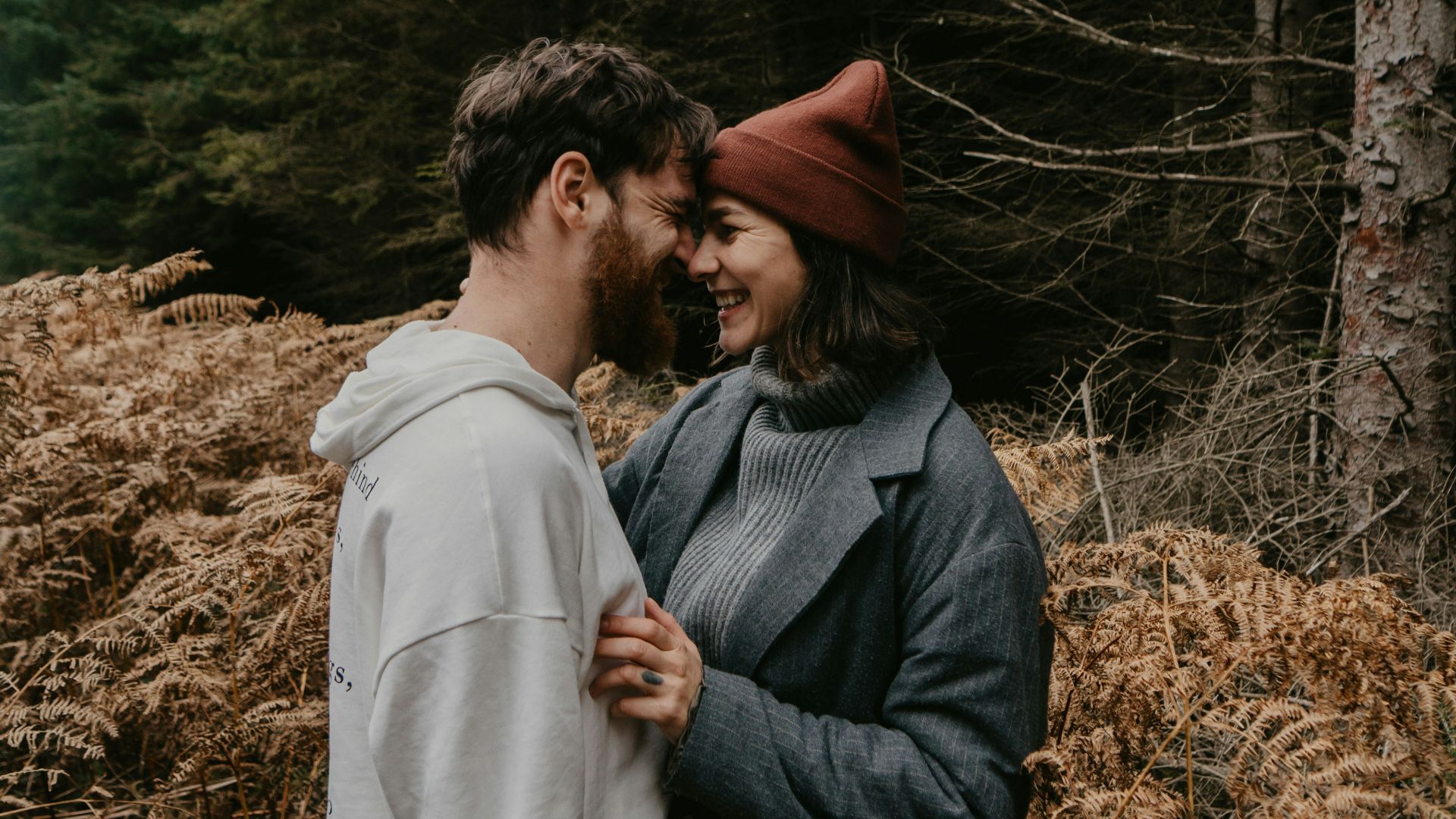 man and woman kissing on brown grass field during daytime