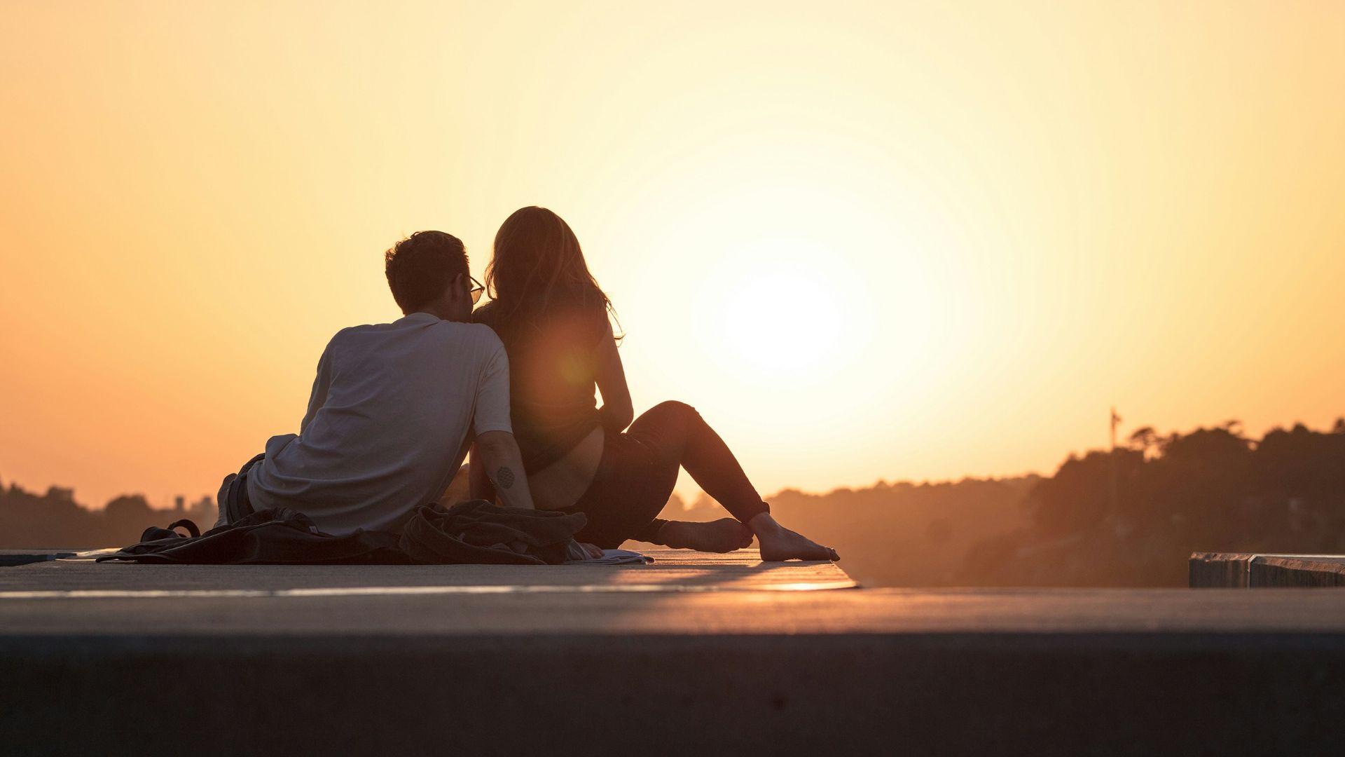 couple sitting near trees during golden hour