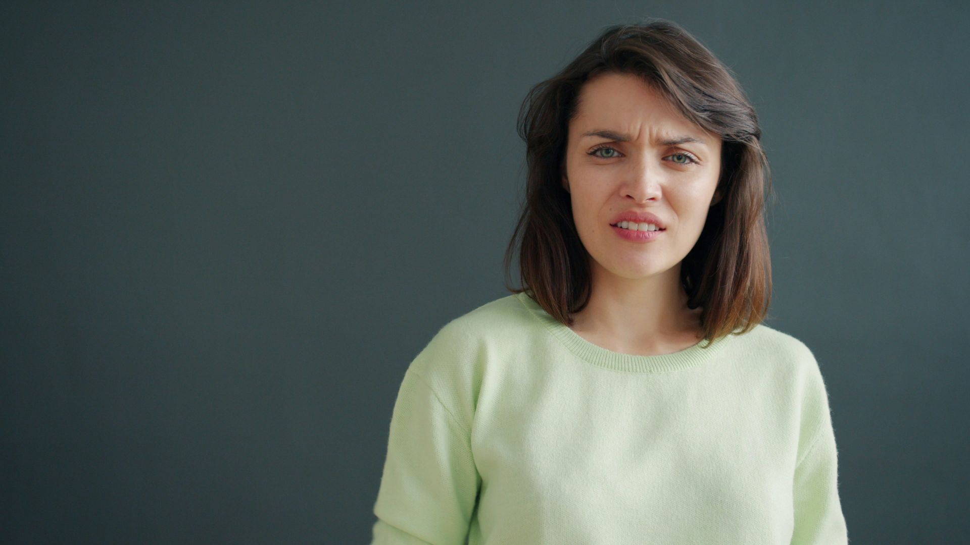 Woman with a disgusted expression against a dark background