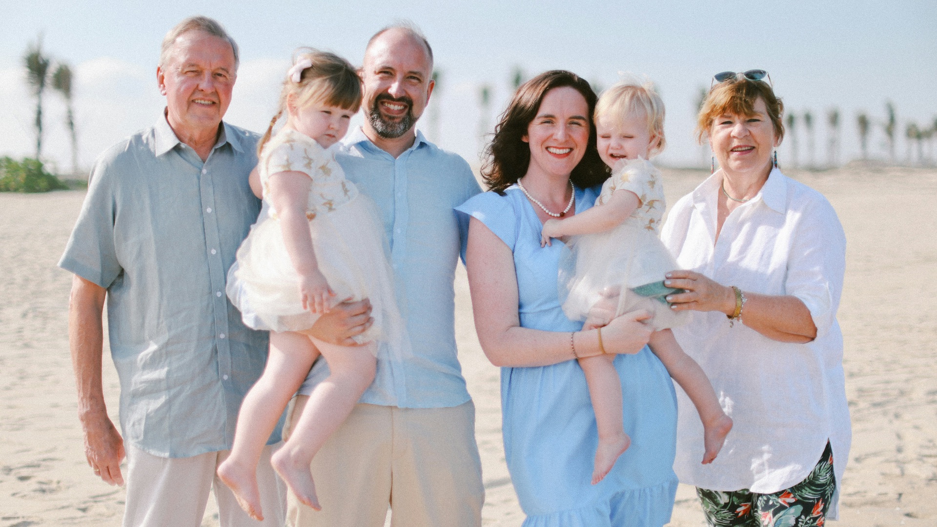 A multi-generational family posing on a sandy beach