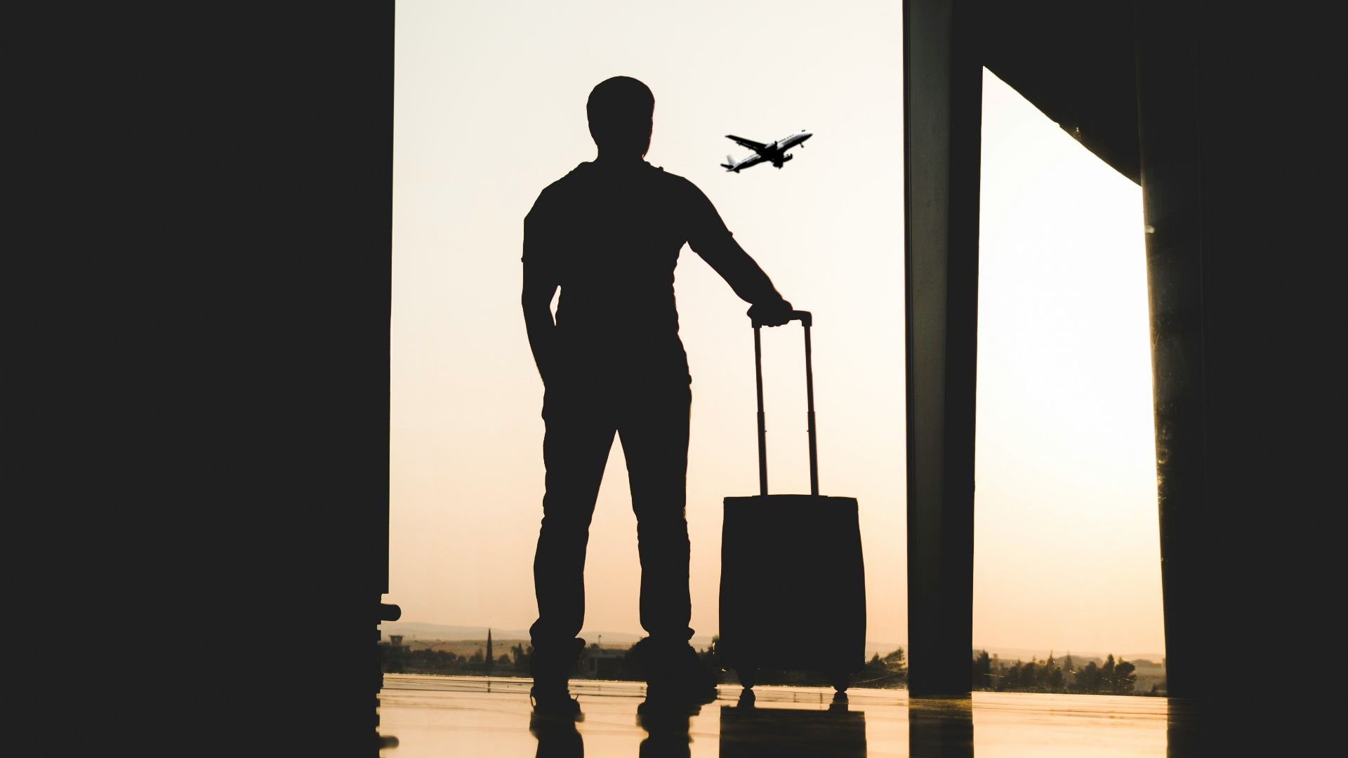 silhouette of man holding luggage inside airport