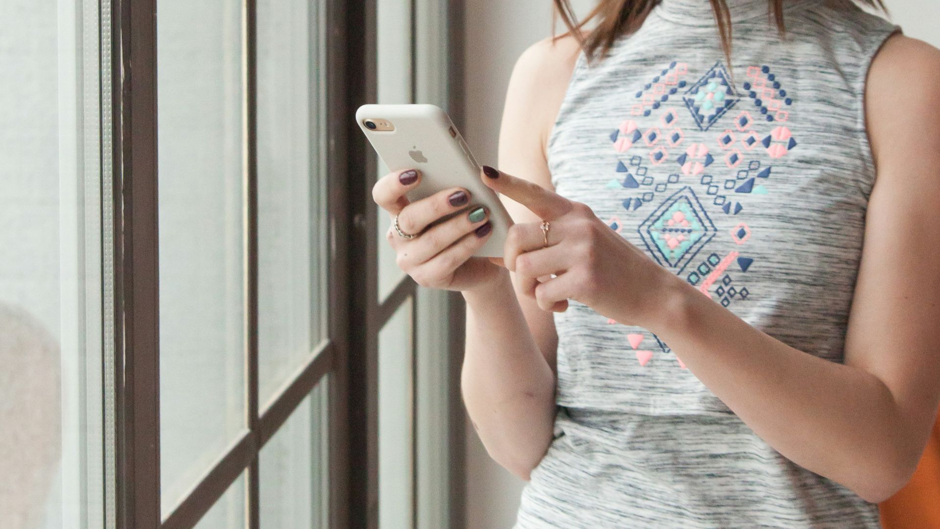 woman in gray tank top holding white smartphone