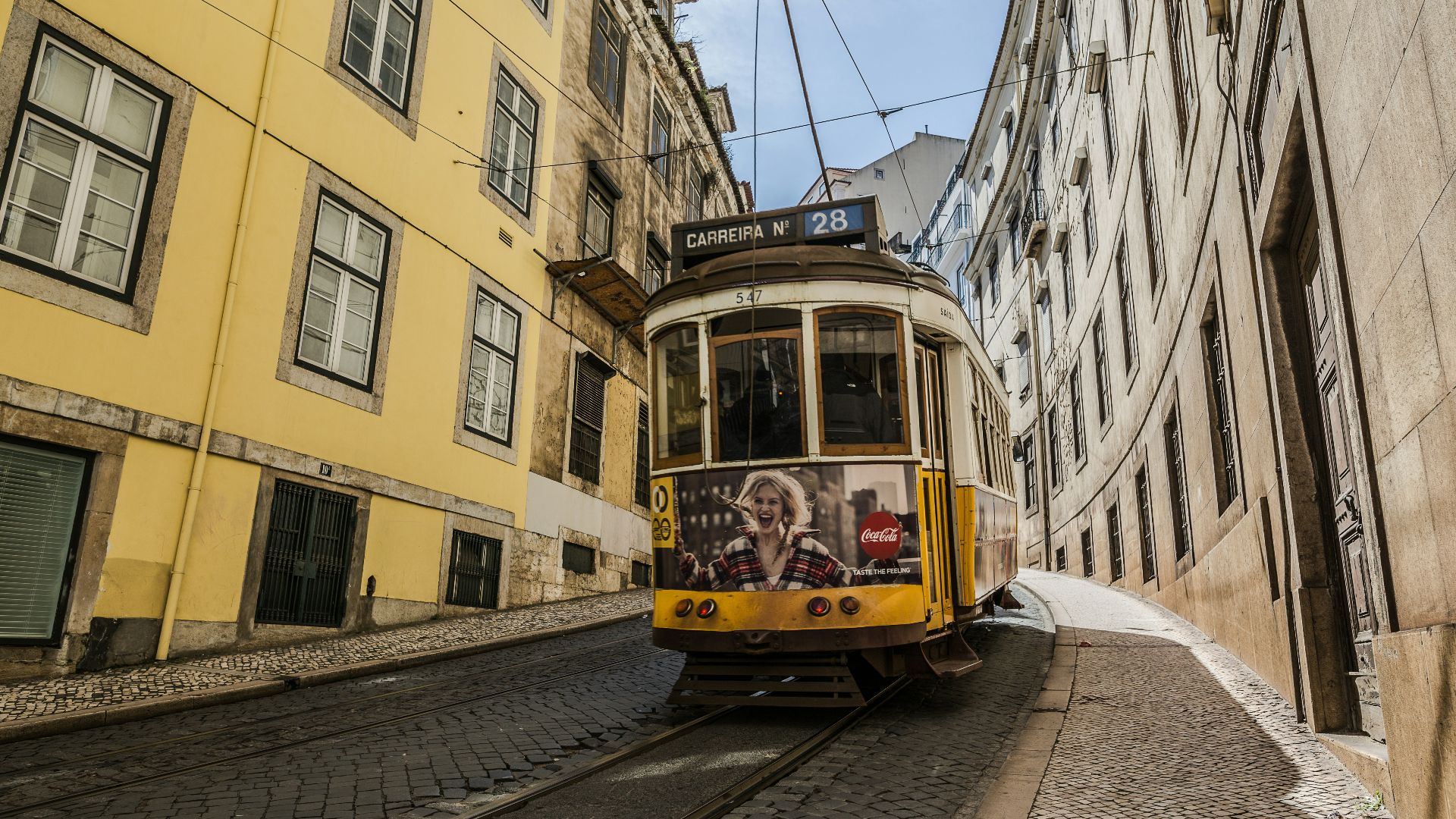 yellow tram car in between buildings