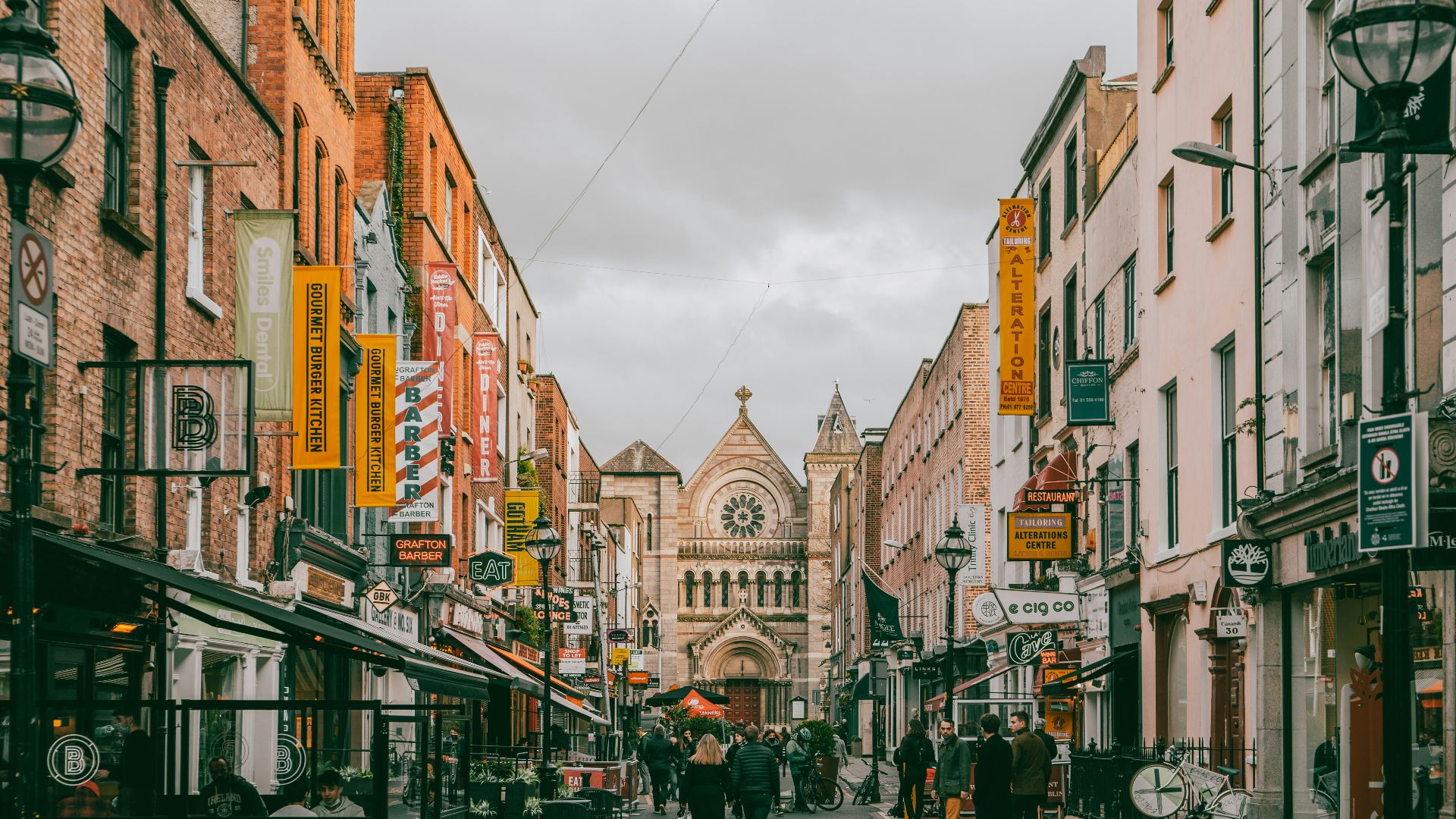 a group of people walking down a street next to tall buildings