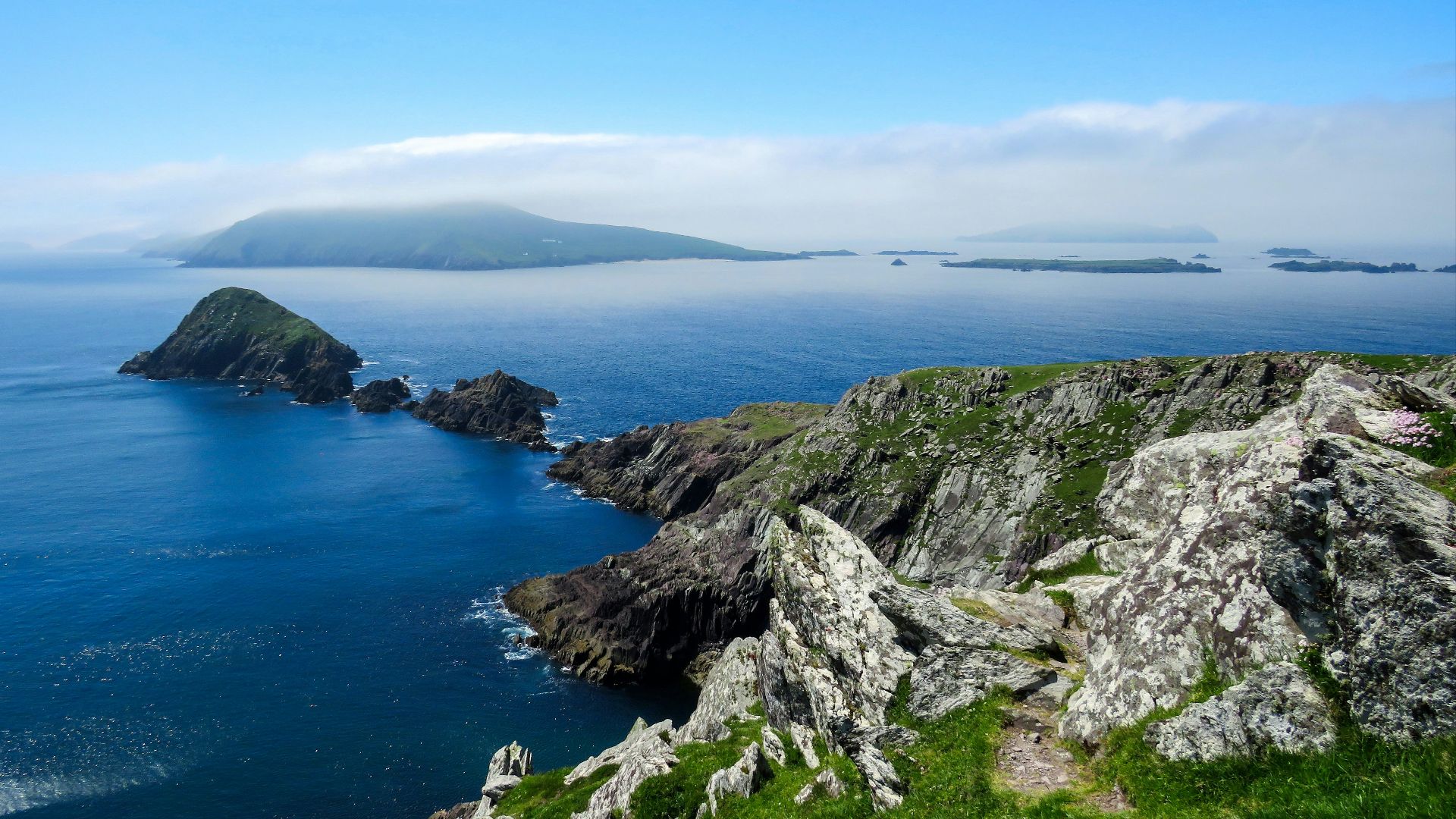 green and gray rock formation near blue sea under blue sky during daytime