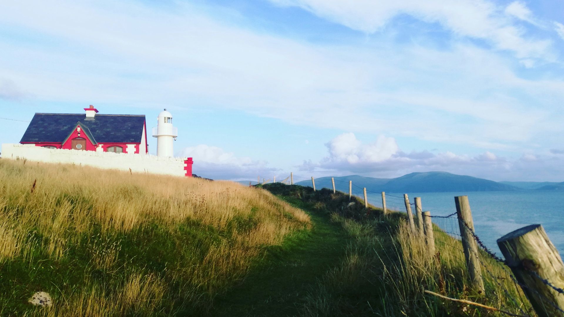 white and red lighthouse near green grass field under blue sky during daytime