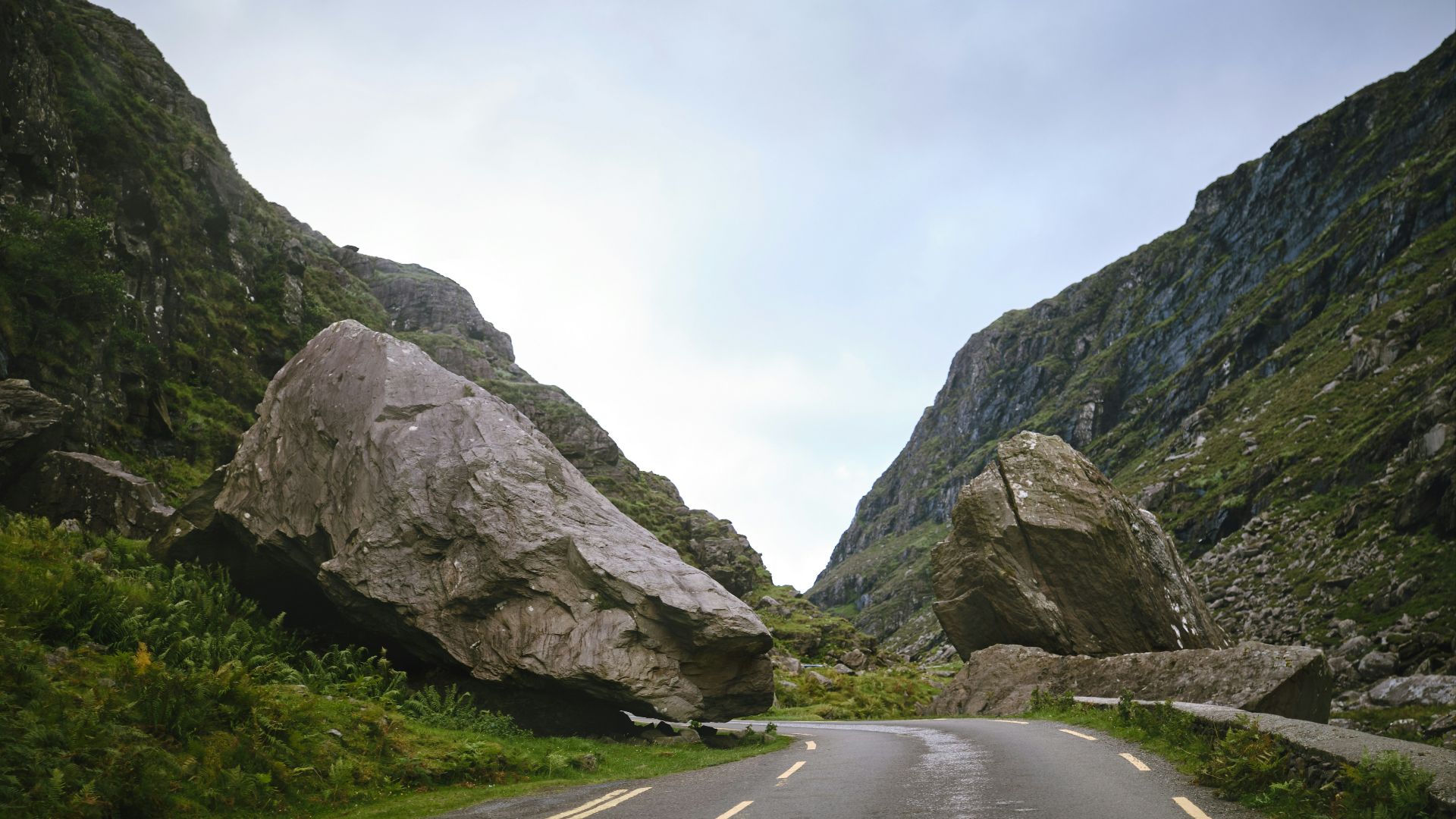a car driving down a road next to large rocks