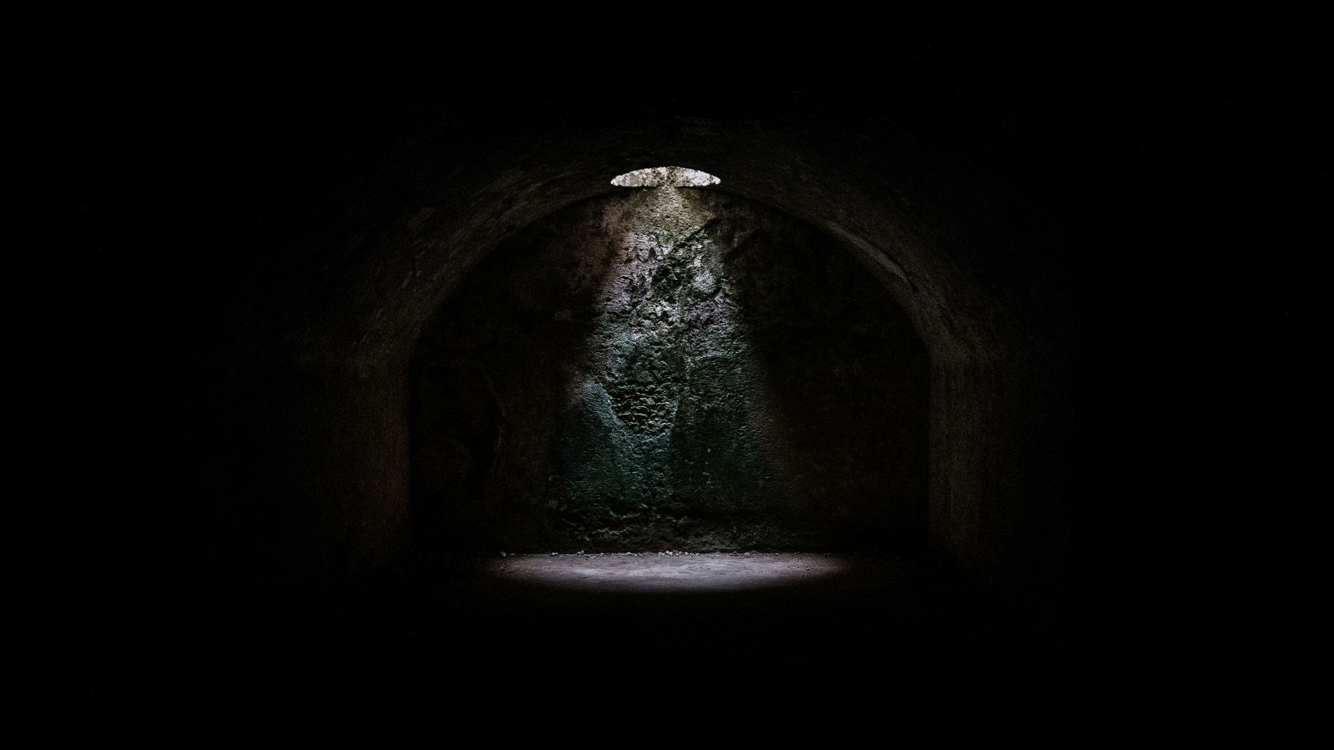 A spotlight coming from a hole in a dark underground cave in Minorca