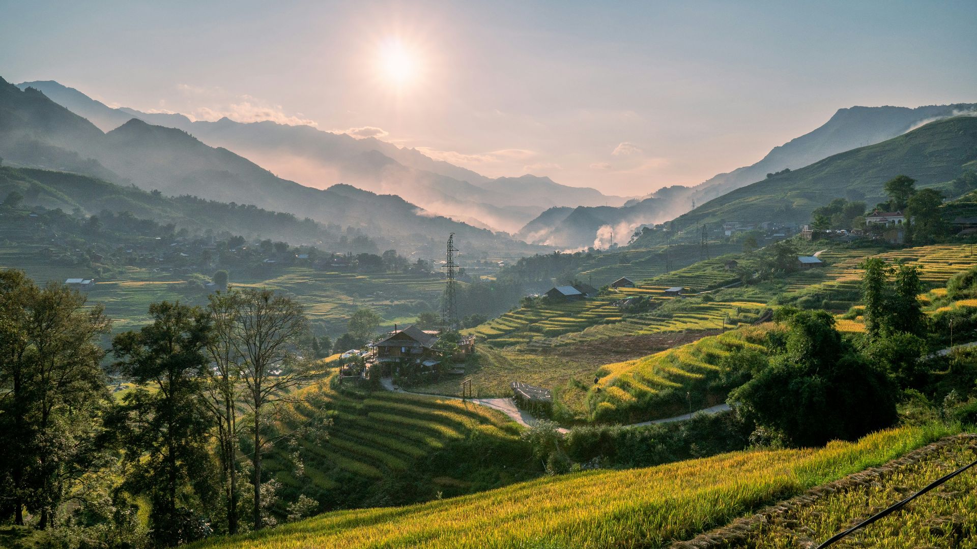 the sun is setting over a green valley