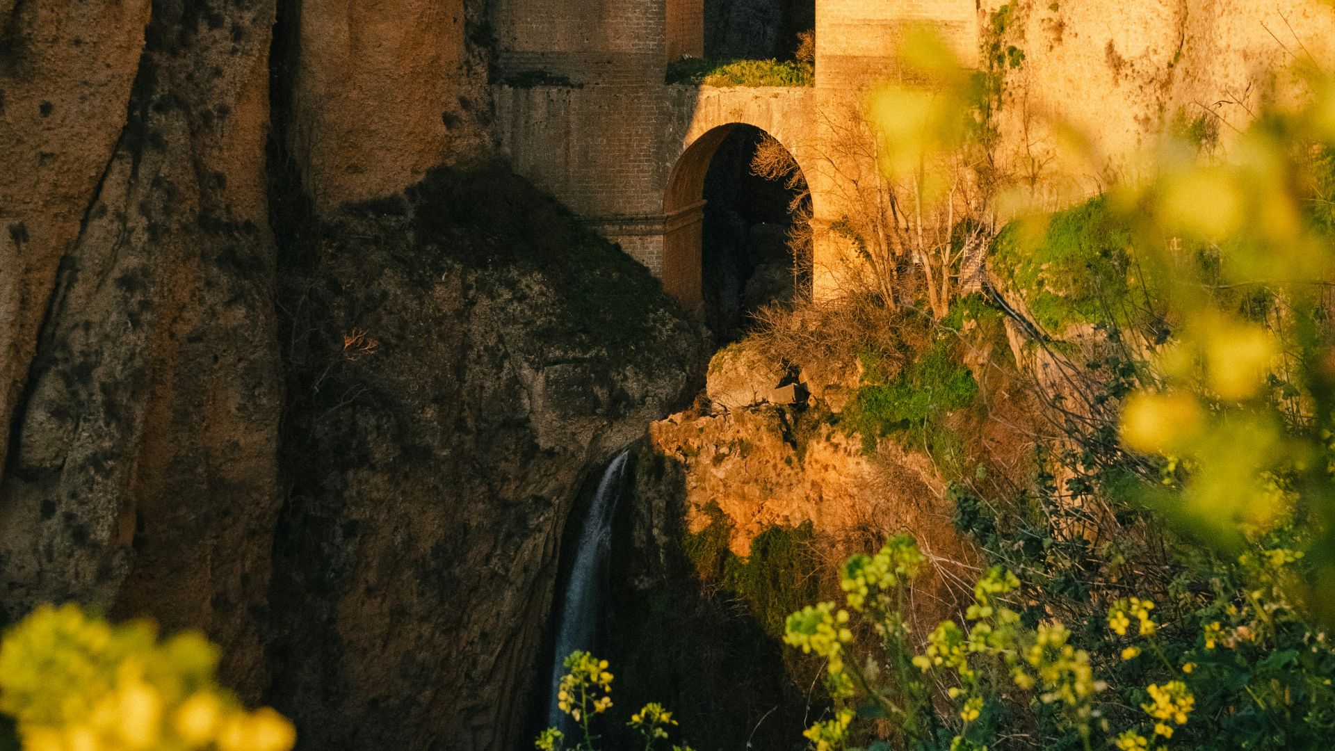 a stone bridge over a river next to a cliff