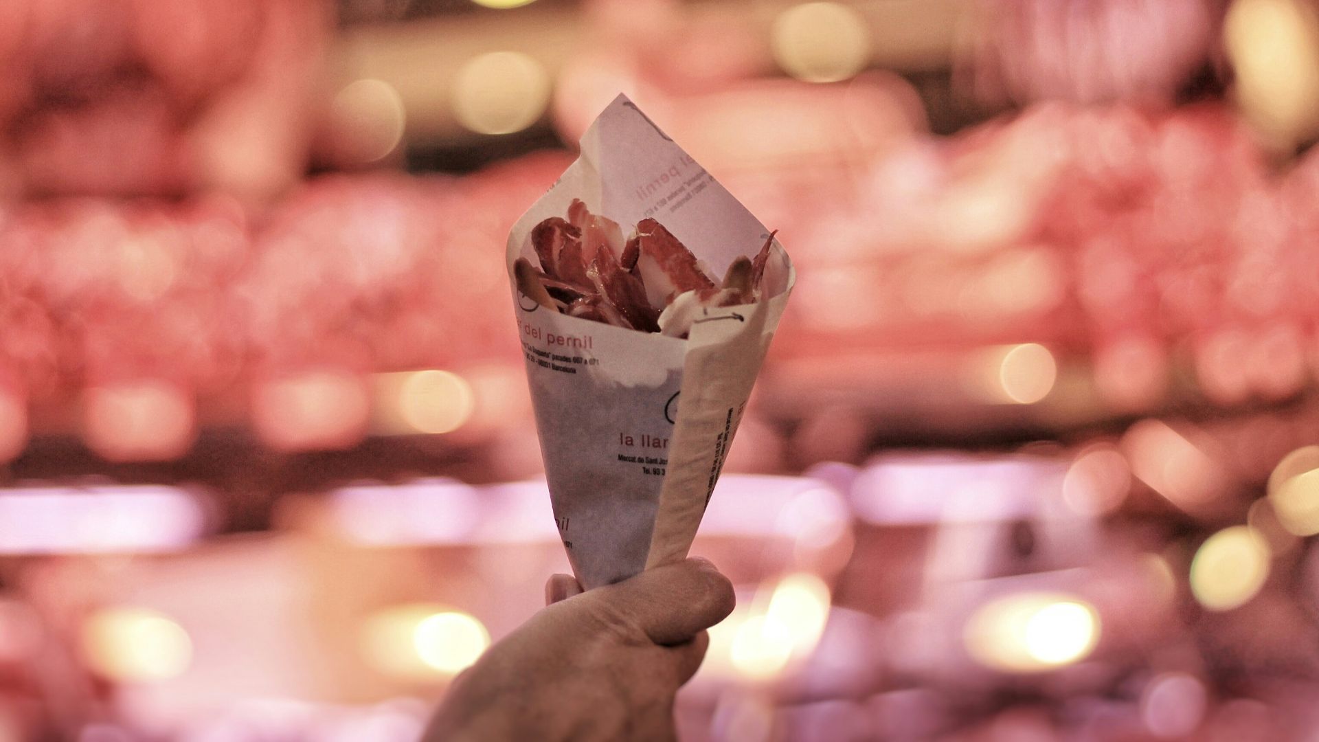 a person holding up a paper cone filled with food