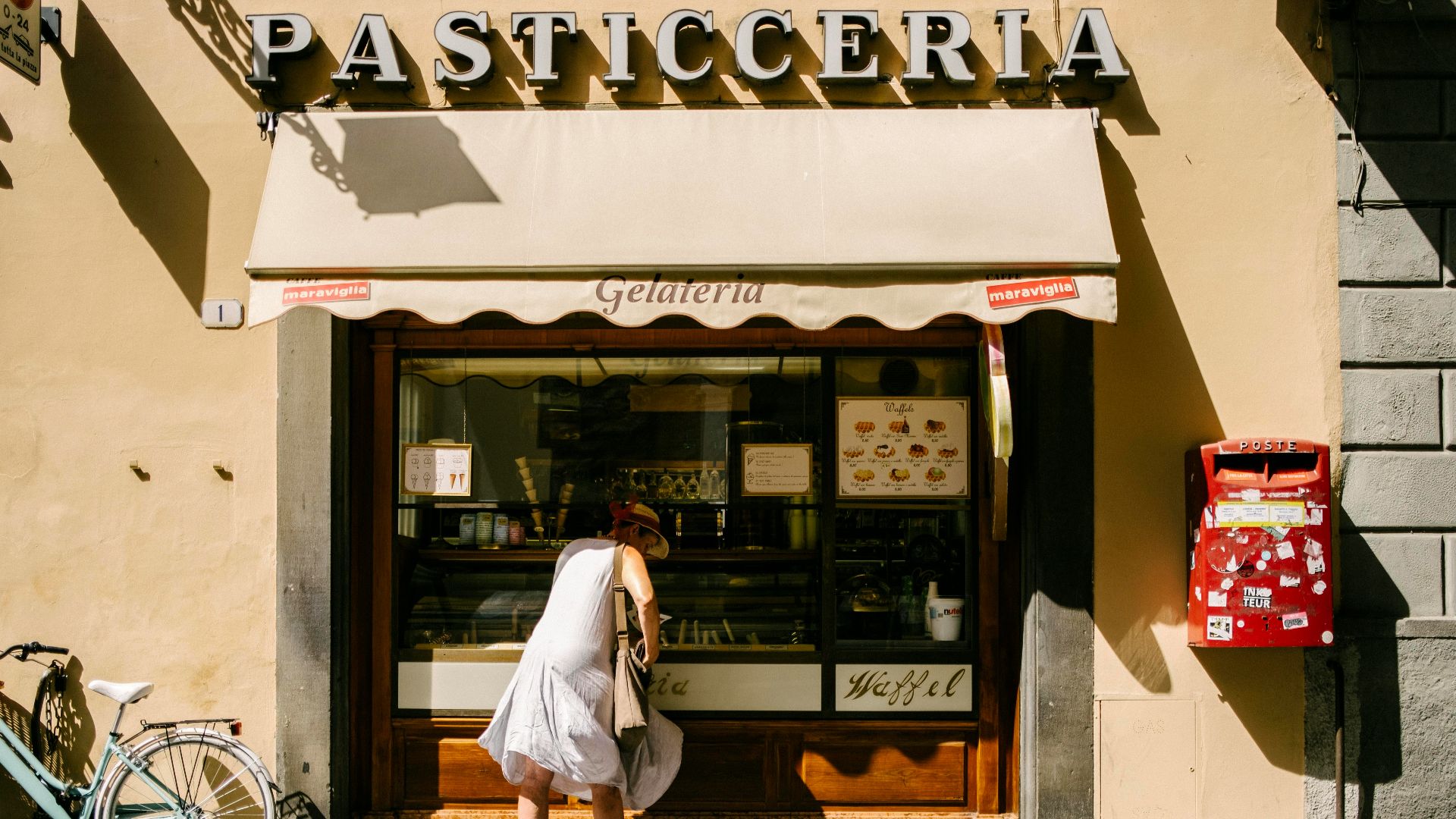 man in white shirt and white pants standing in front of brown and white building during