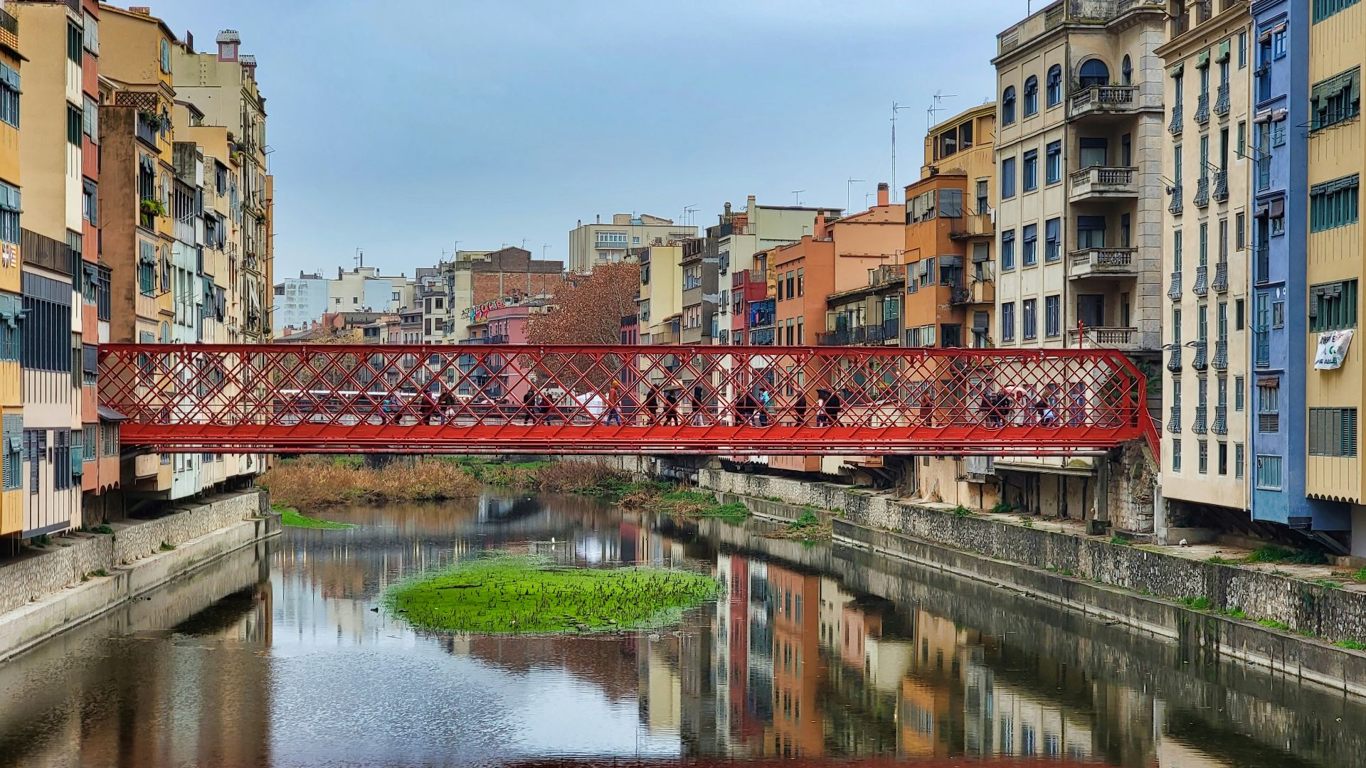 a red bridge over a river in a city