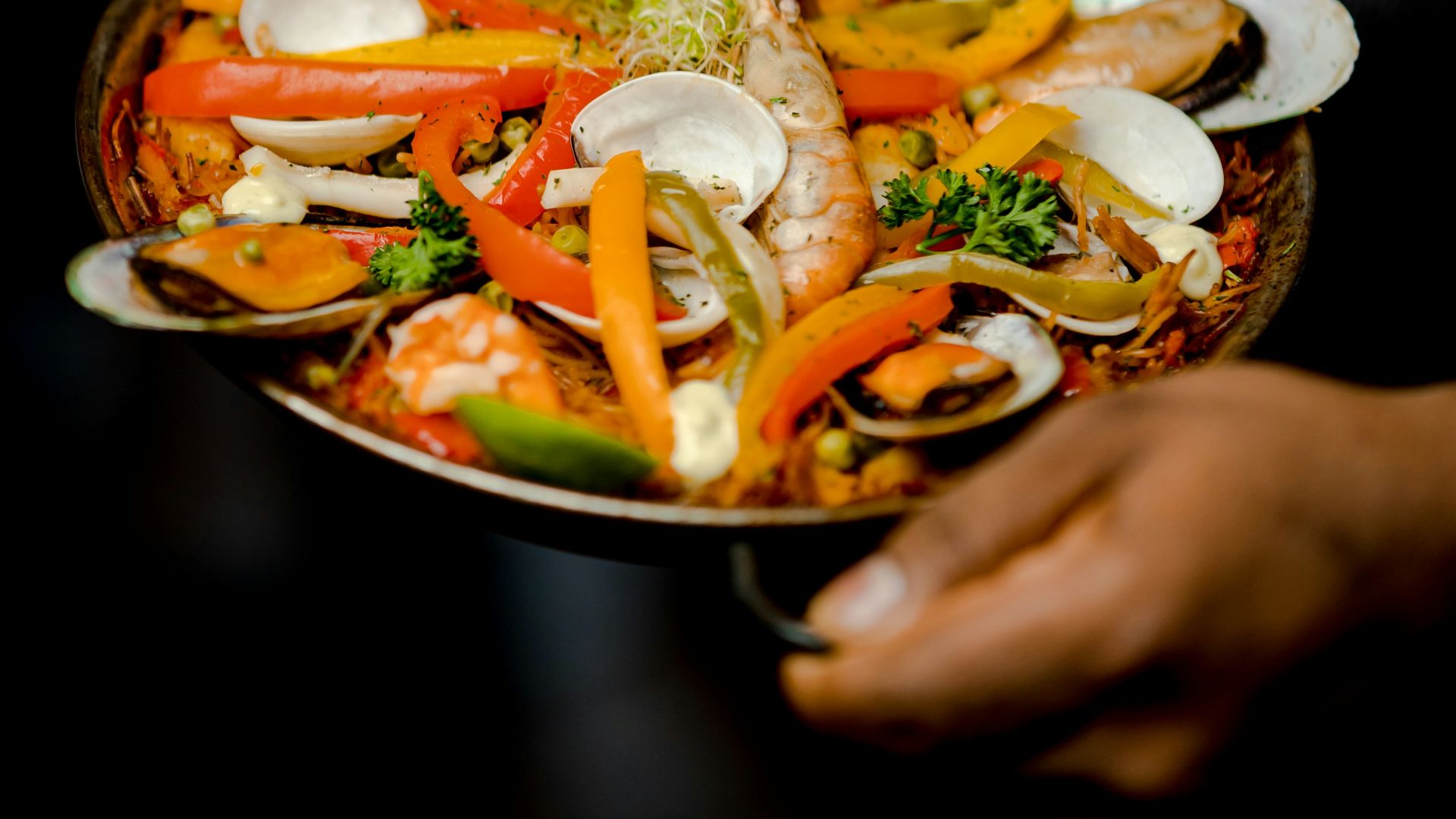 a person holding a plate of food with shrimp and vegetables