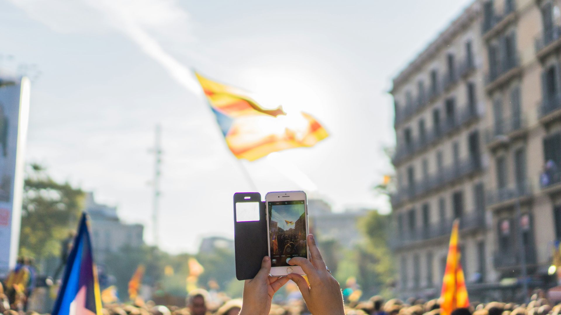person taking photo of yellow and blue flag through silver iPhone 6 with black flip case during daytime