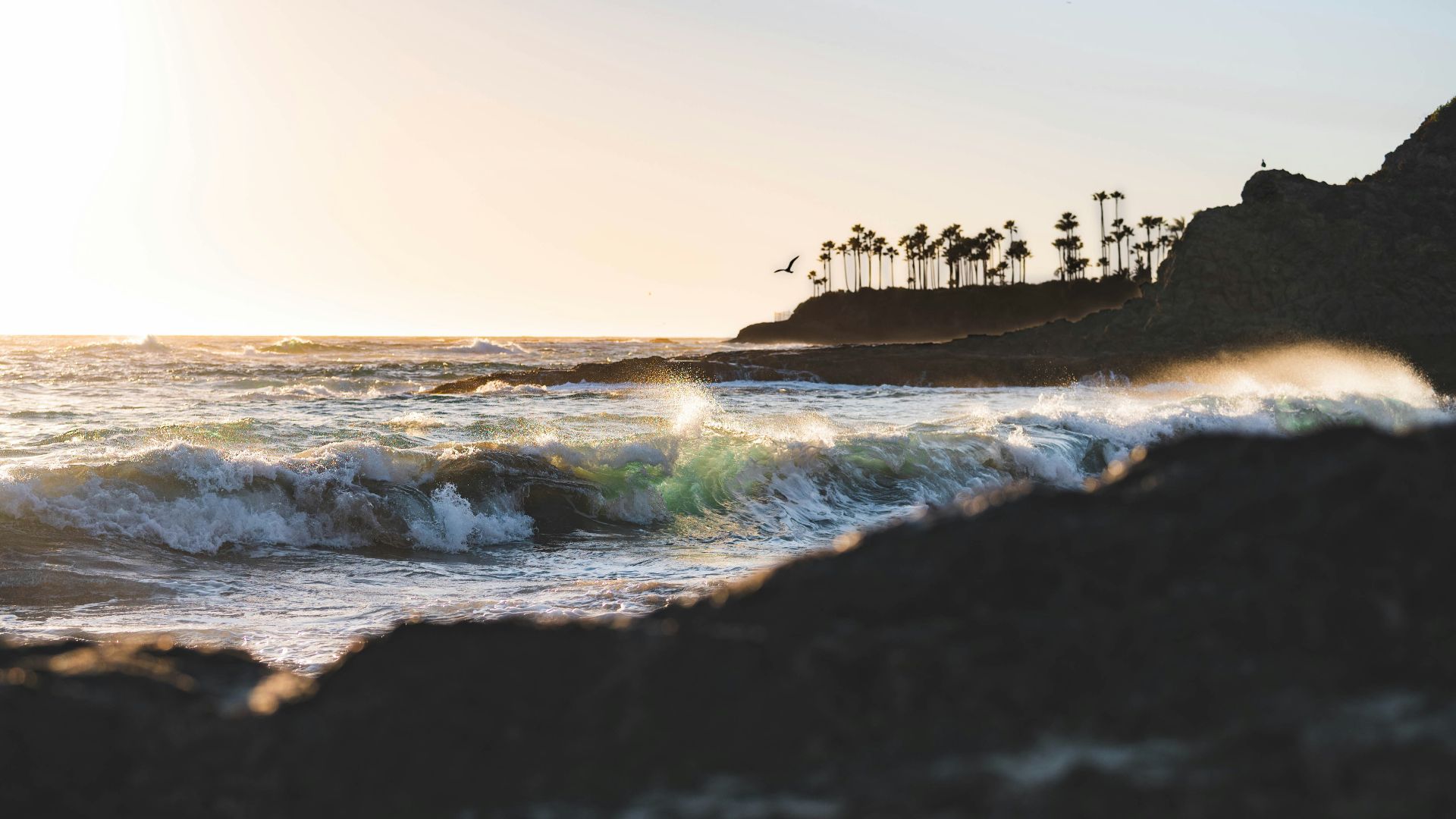ocean waves crashing on shore during sunset