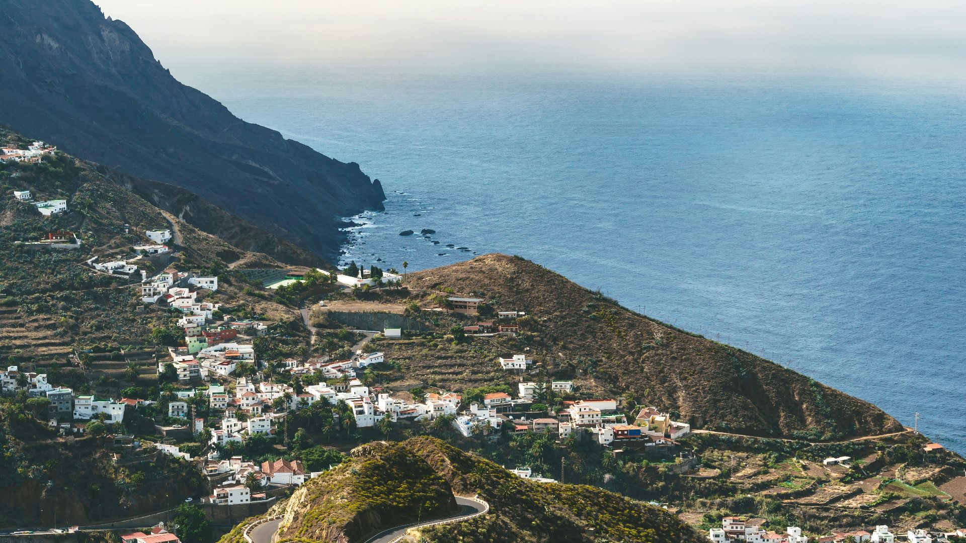 Coastal village nestled on a green mountainside overlooking the ocean.