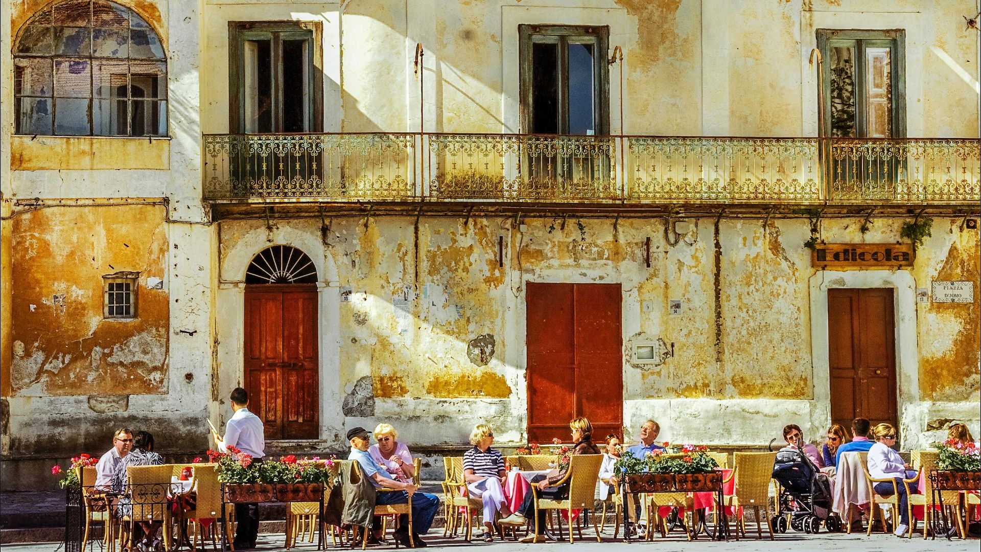 people sitting on chairs near brown concrete building during daytime