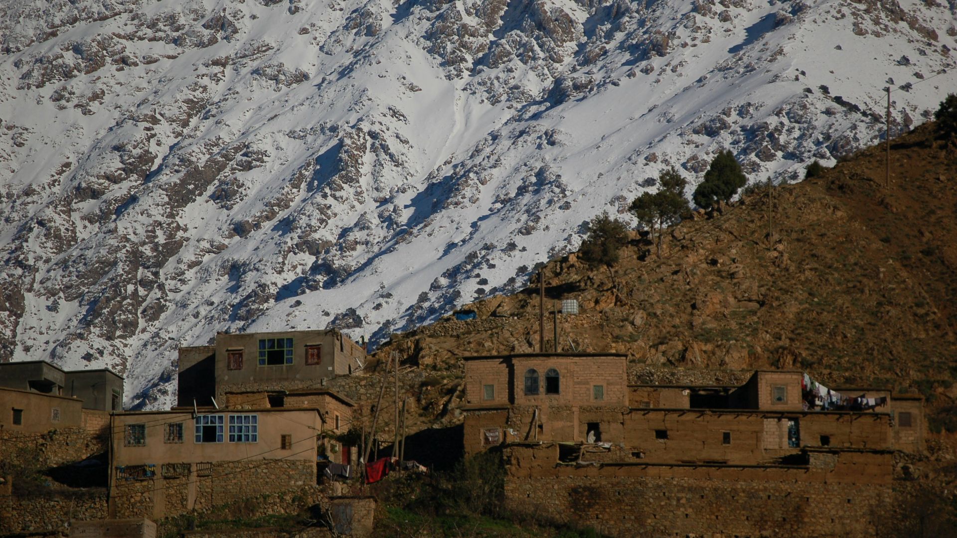 brown concrete building near snow covered mountain during daytime