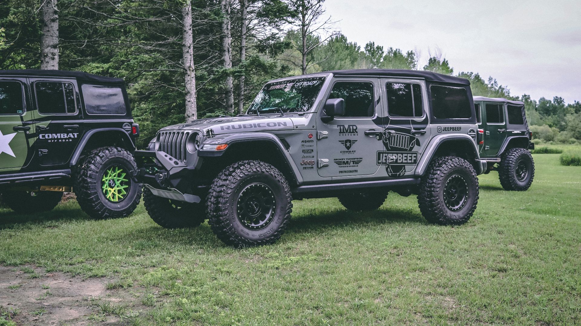 two jeeps are parked in a grassy field