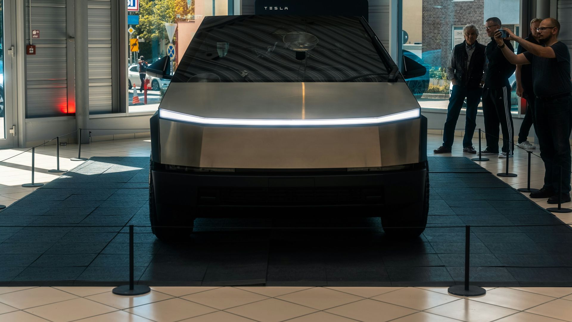 A group of people standing around a car in a showroom