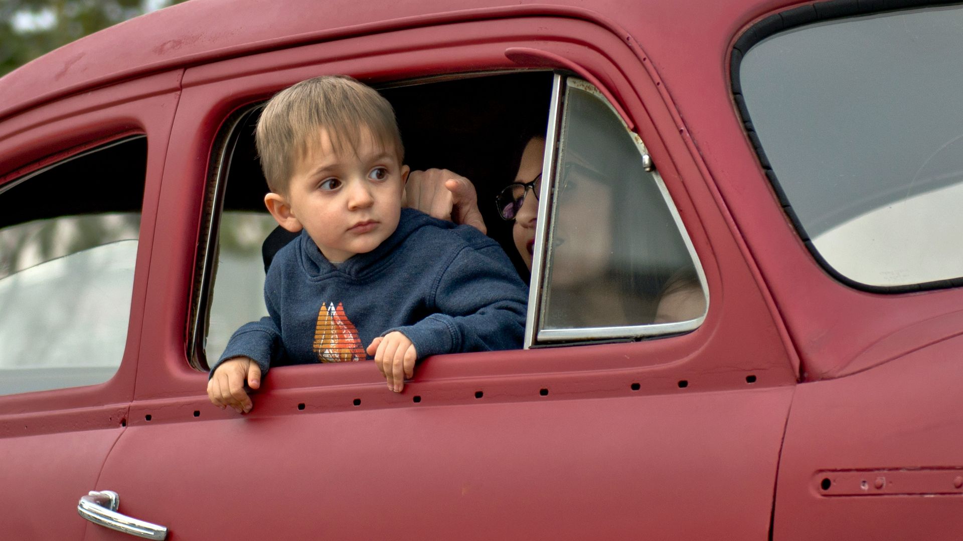 toddler riding on red vehicle