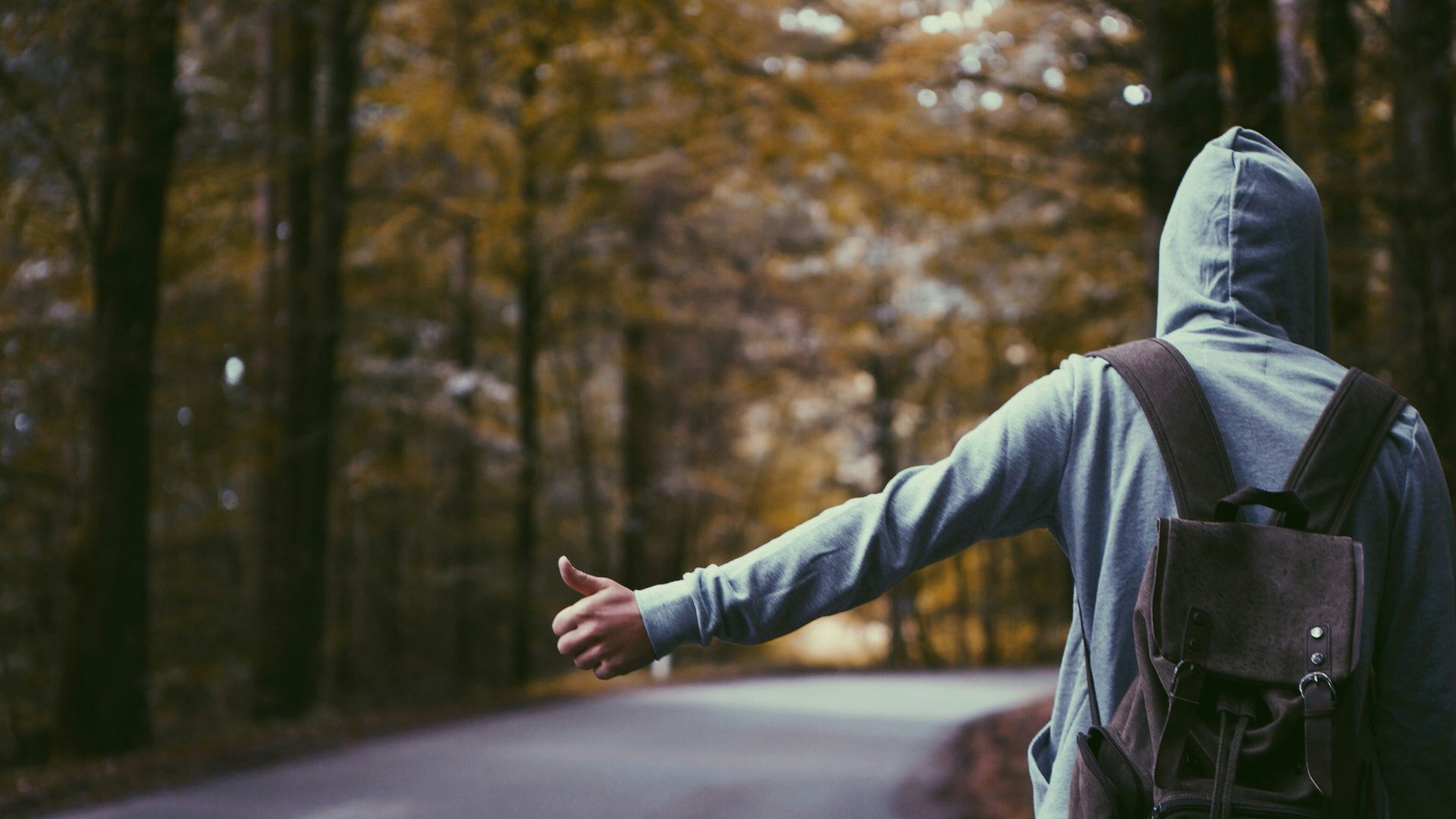 person standing beside road doing handsign