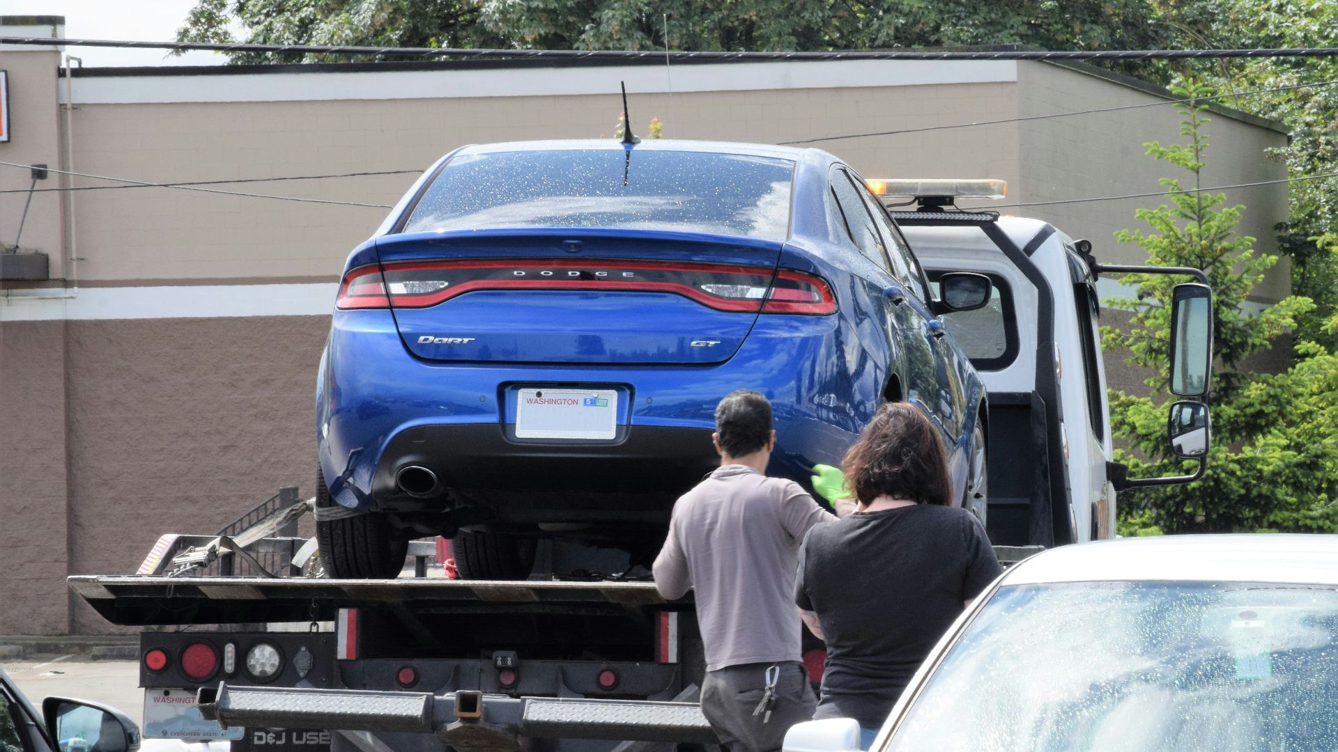 a blue car being loaded onto a flatbed truck