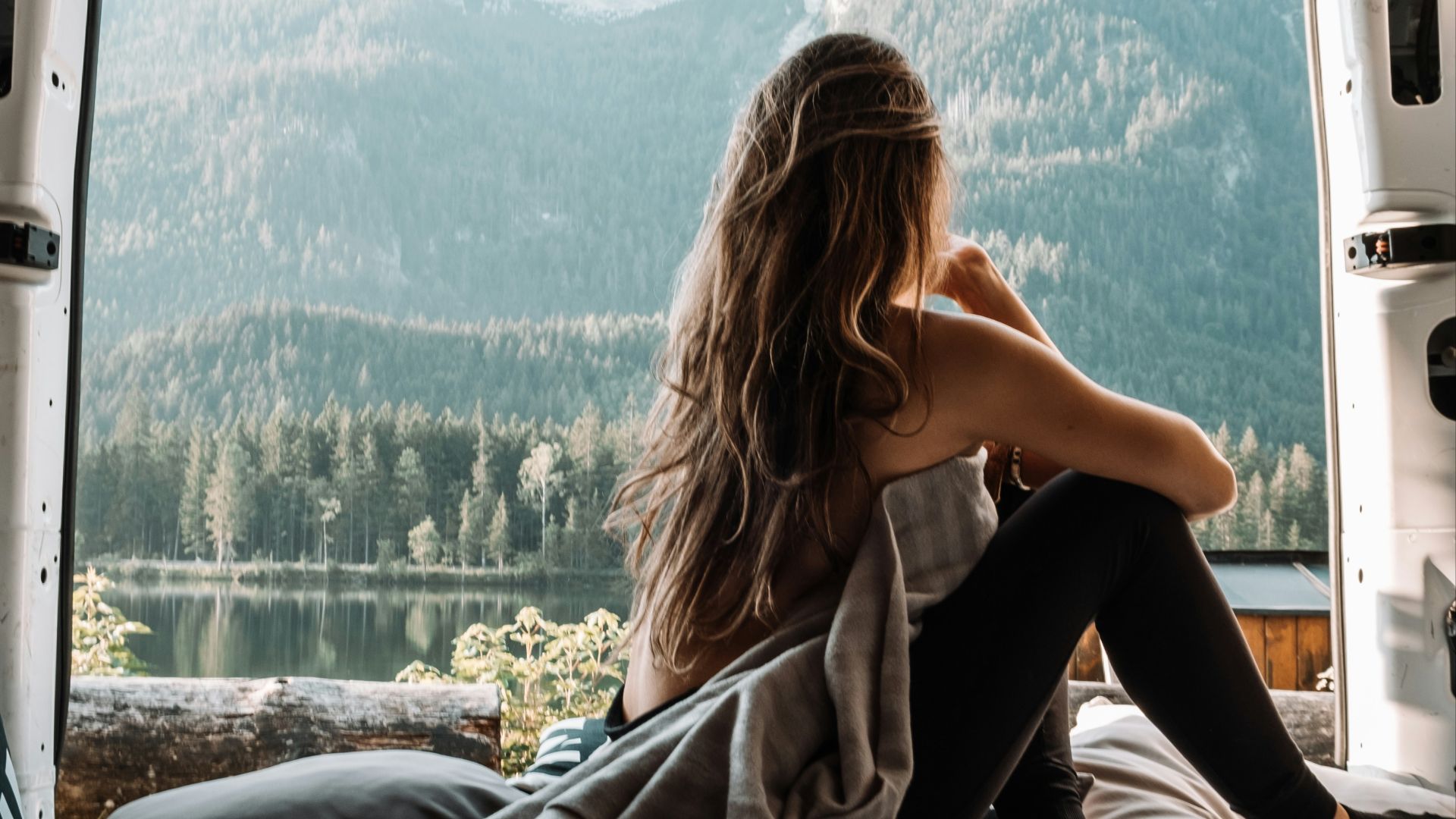 woman in black tank top and black pants sitting on bed