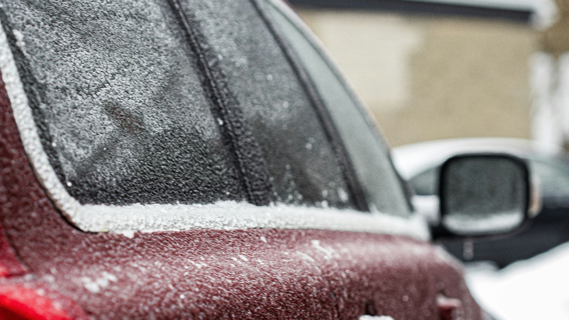 a red car parked on the side of the road covered in snow