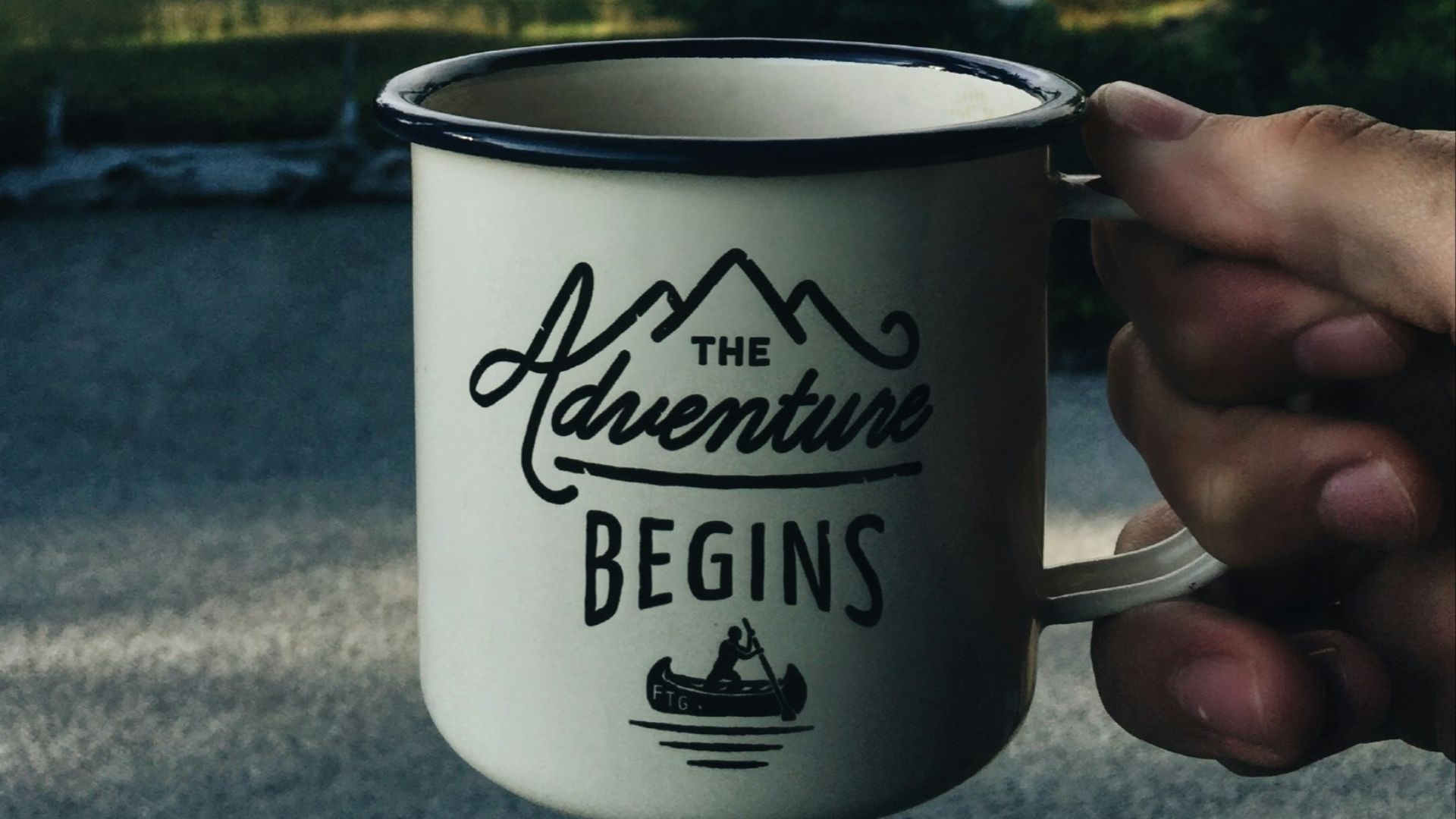 person holding cup with body of water background