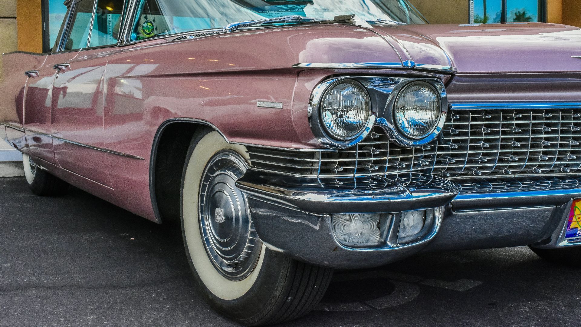 pink classic car parked near concrete building
