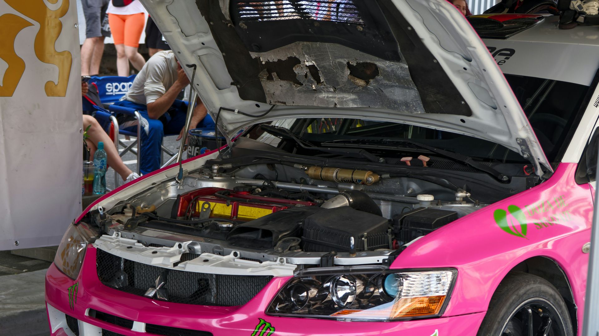 a pink car with a hood open in a showroom