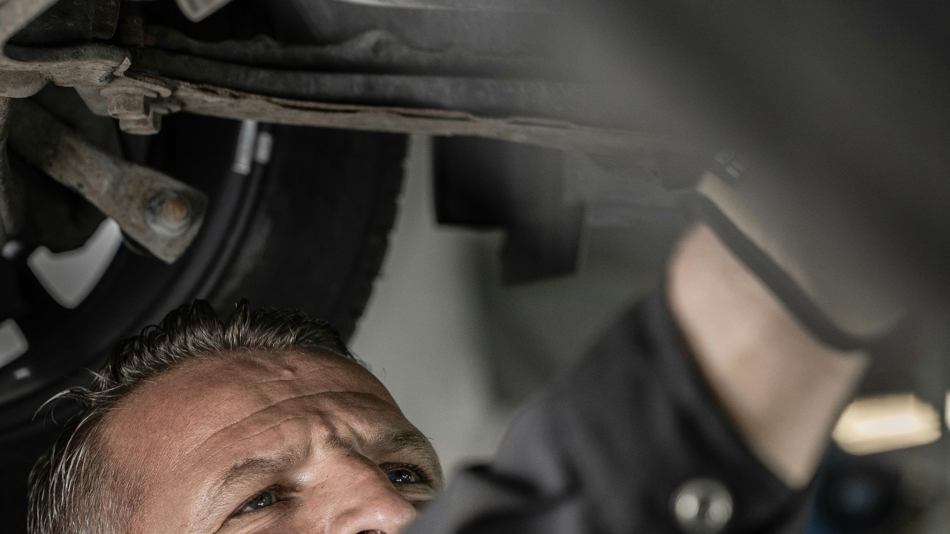 a man working on a car under a vehicle
