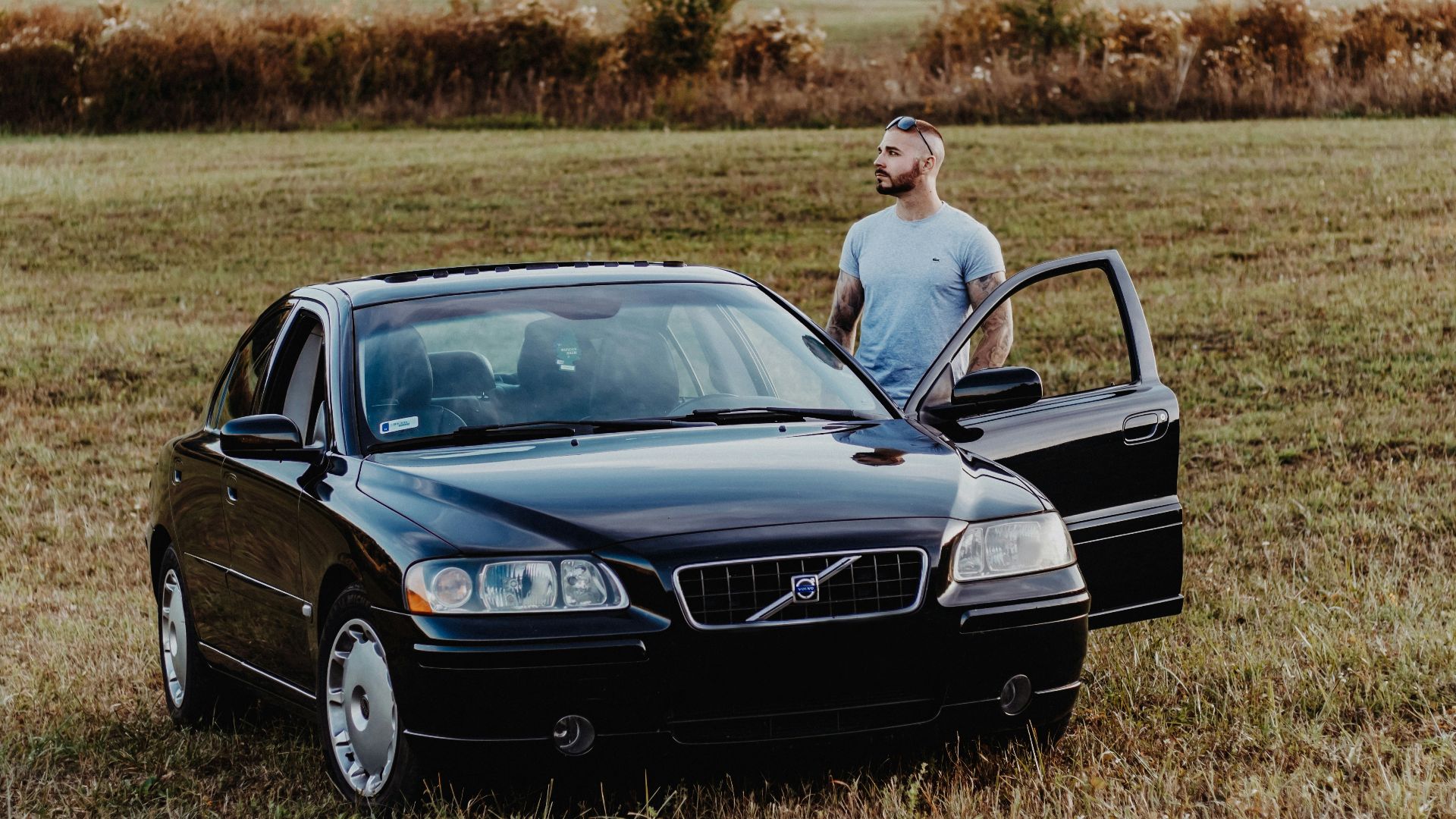 man standing beside black Volve S40 vehicle at daytime
