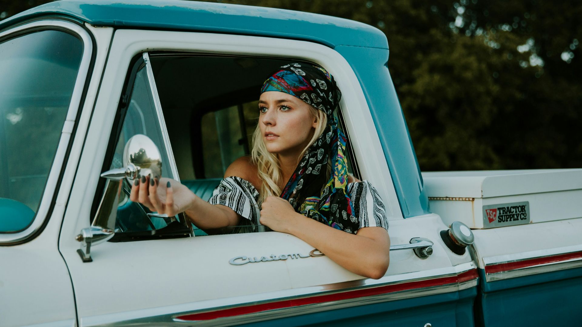 photography of woman holding side mirror in white and green 2-door pickup truck