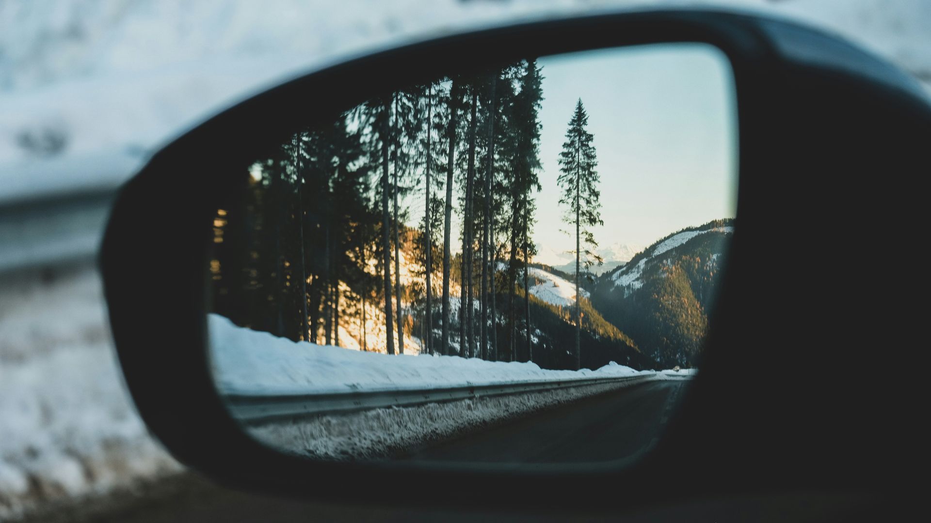 car side mirror showing snow covered trees