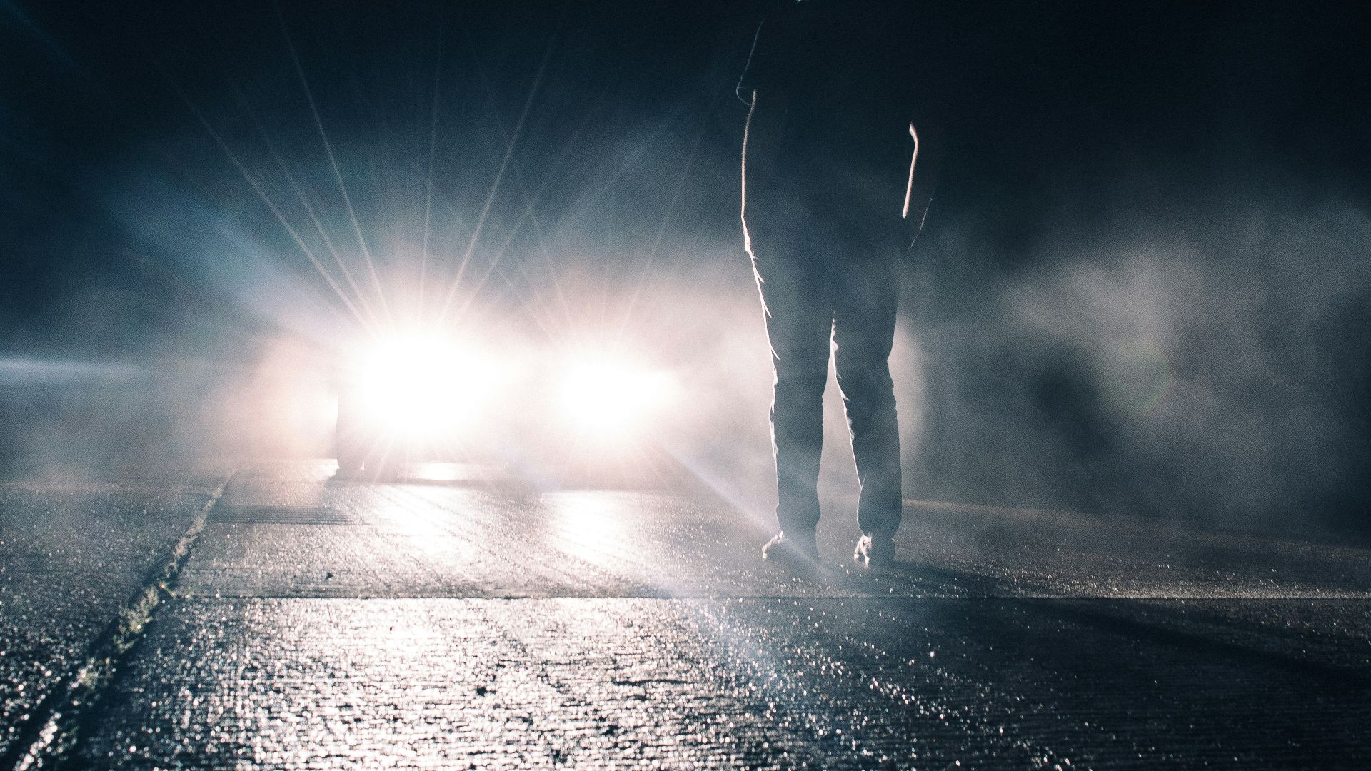 man standing in front of lighted car