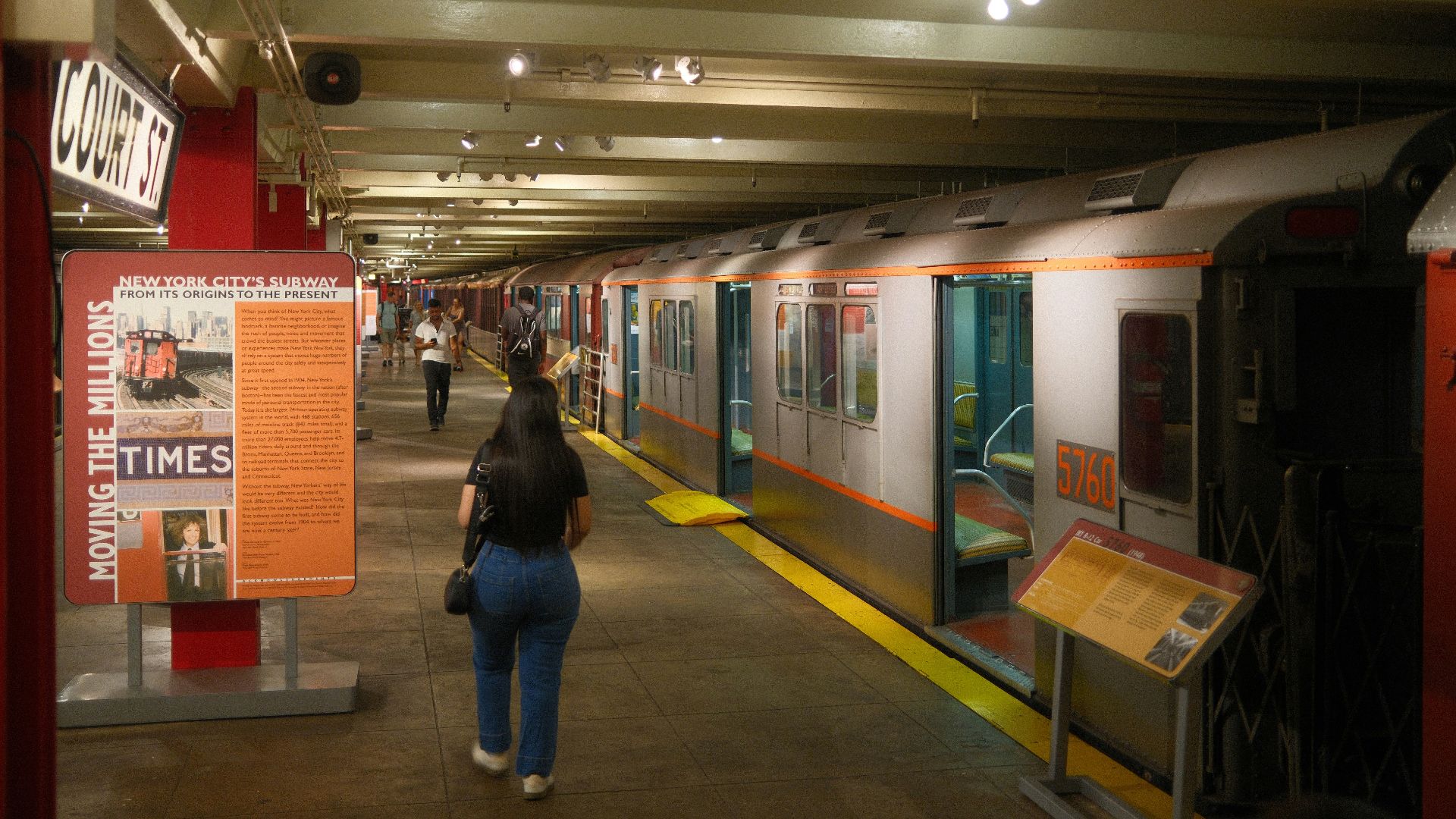 A woman walking down a hallway next to a train