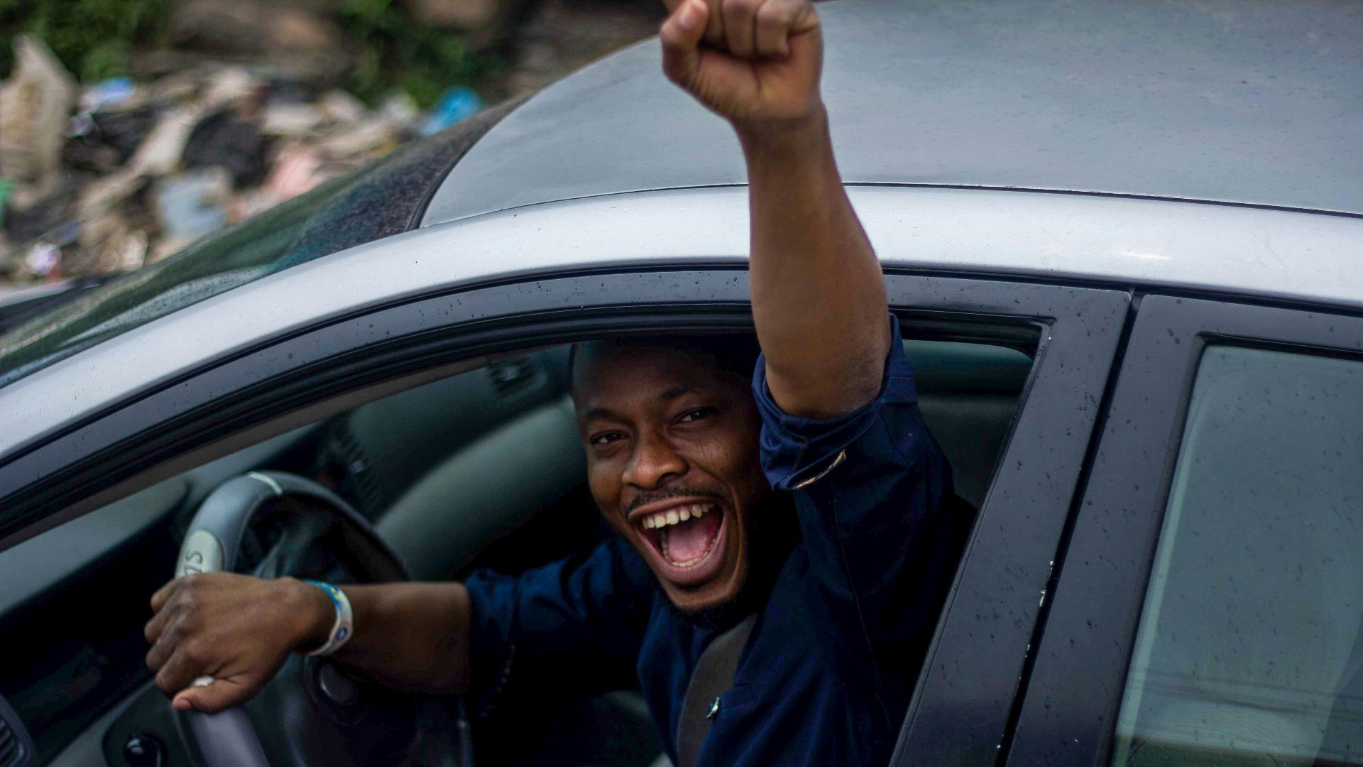 man in black t-shirt and blue denim jeans sitting on car seat
