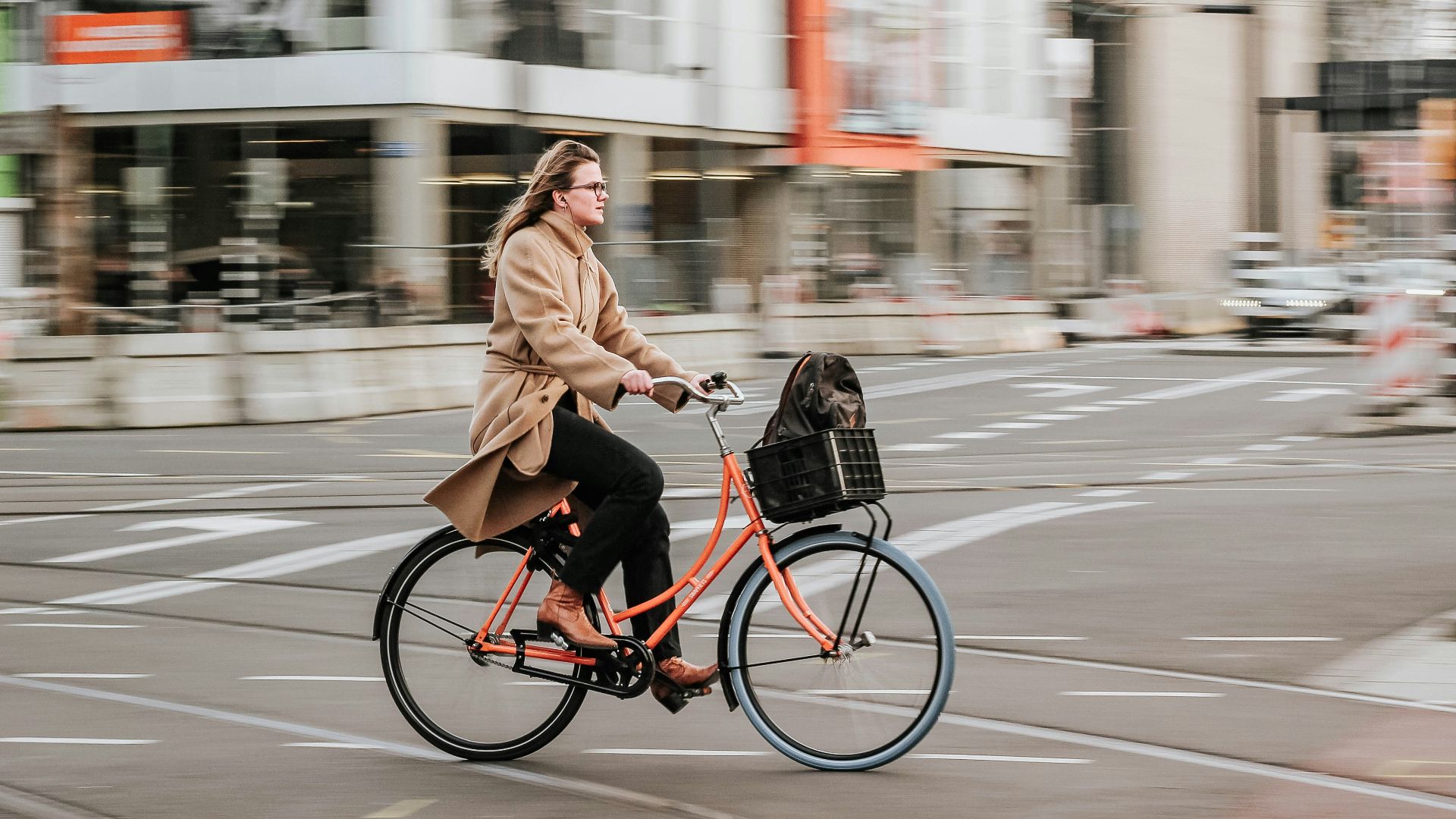 woman in brown coat riding on black bicycle on road during daytime