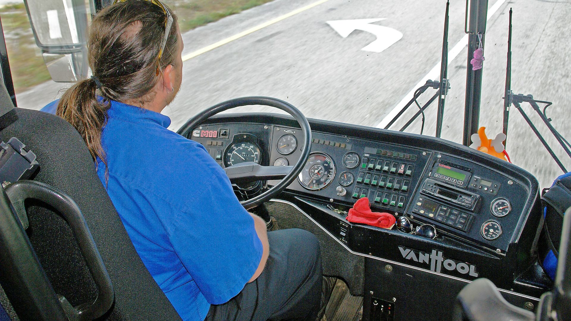 Driver in blue shirt operating a bus dashboard