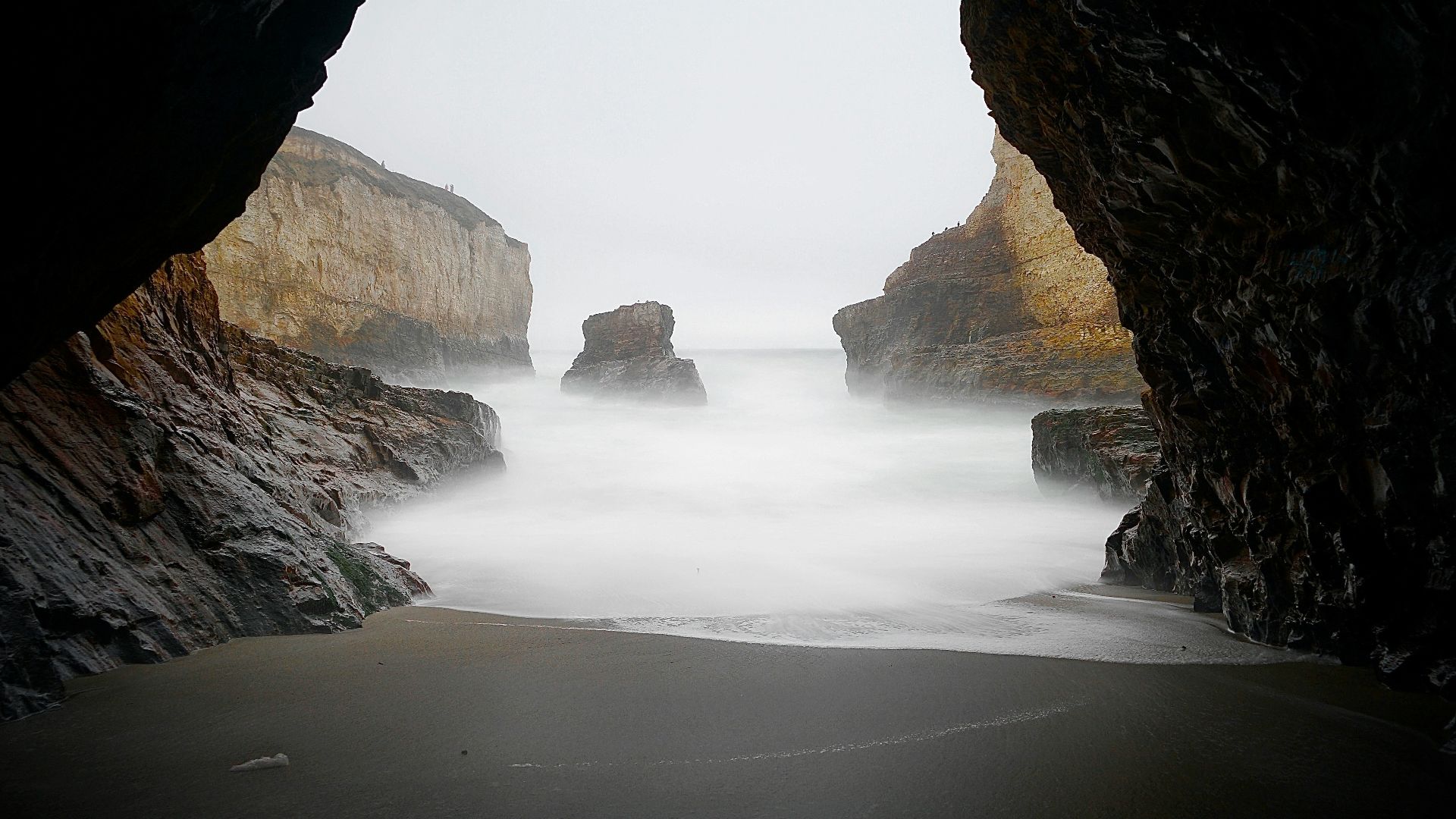 brown cave near body of water during daytime