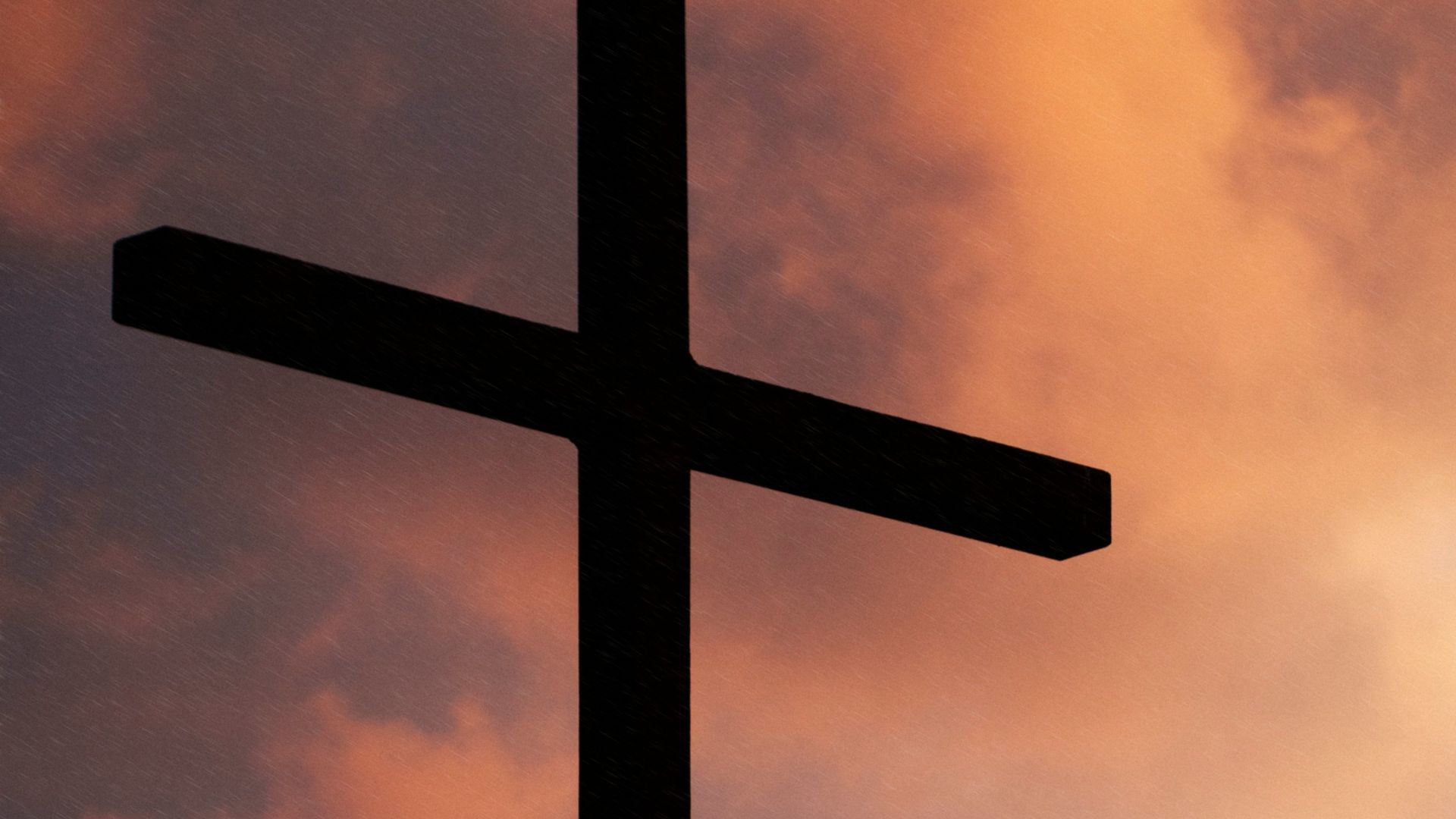 silhouette of large cross under orange sky