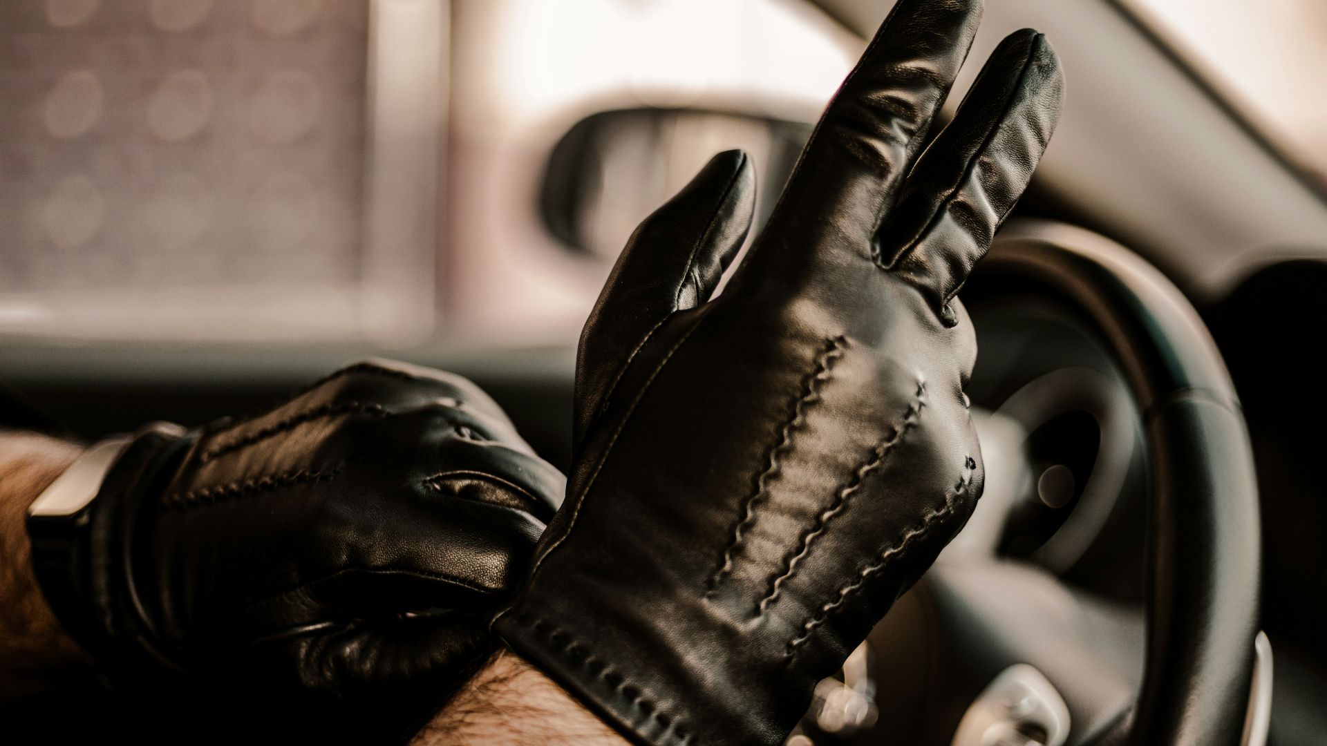 a man wearing black leather gloves driving a car