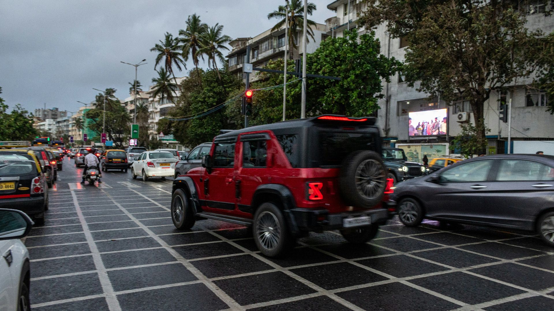 A red suv is driving on a wet road.