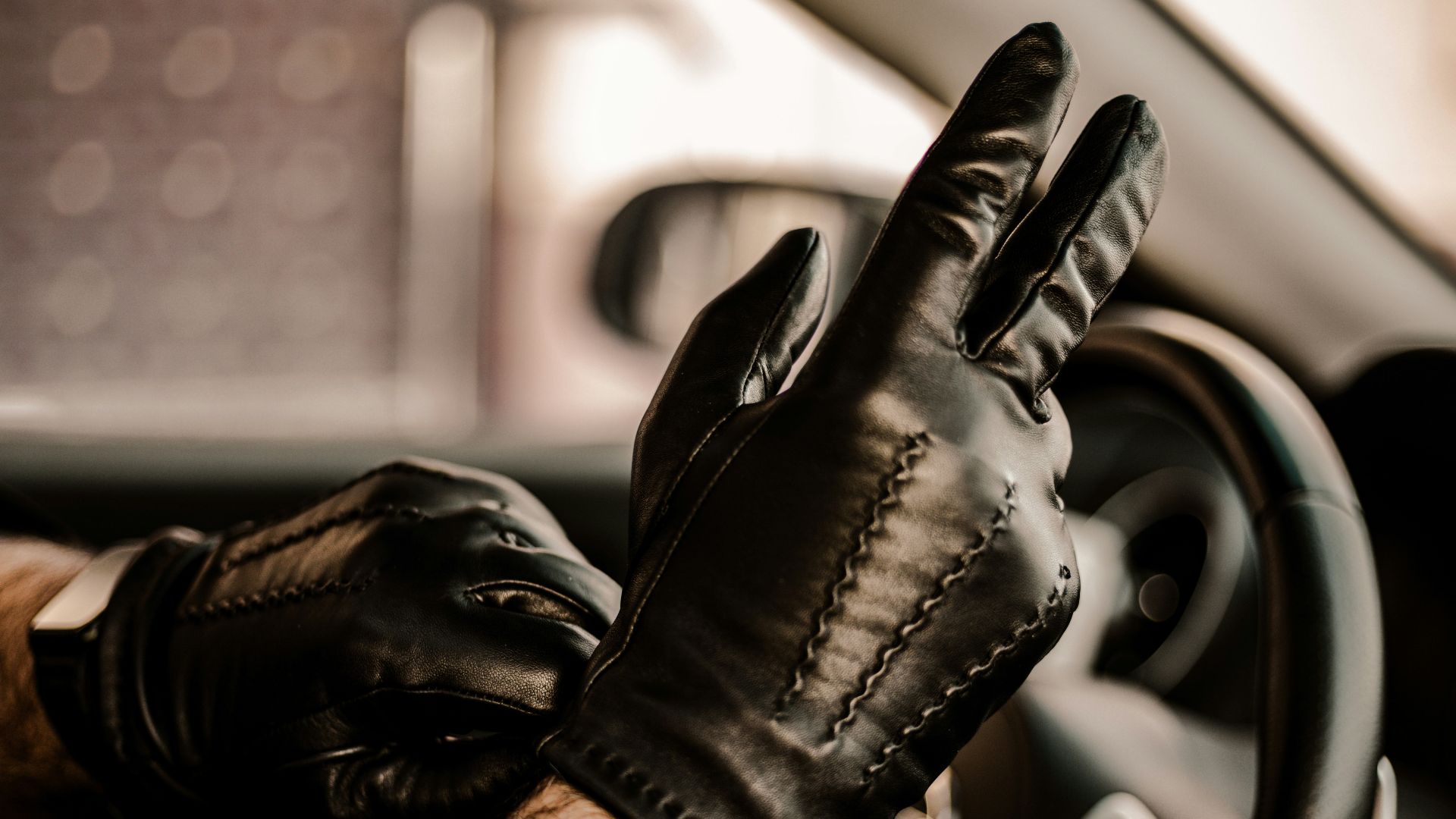 a man wearing black leather gloves driving a car